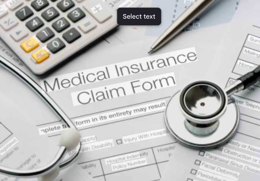 Medical insurance claim form with a stethoscope, a calculator, and a pen on top.