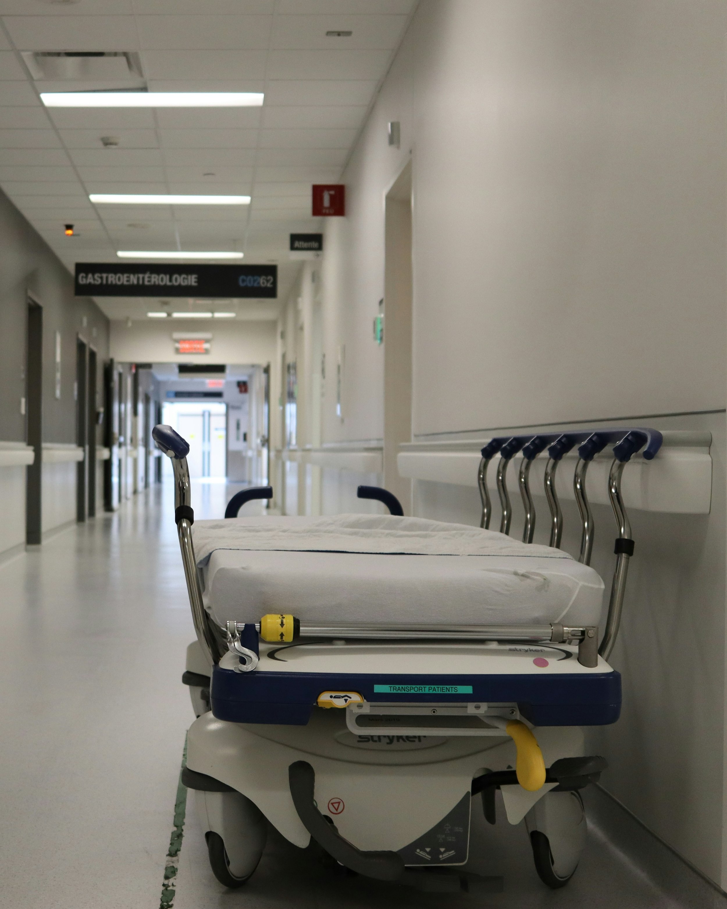 An empty hospital corridor with an empty gurney in the foreground.