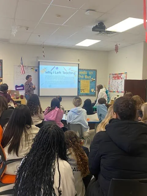 Former educator speaking to future teachers during a high school classroom presentation