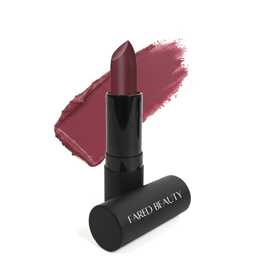 A black tube of lipstick with the brand name 'FARED BEAUTY' lying beside a swatch of mauve lipstick on a white background.