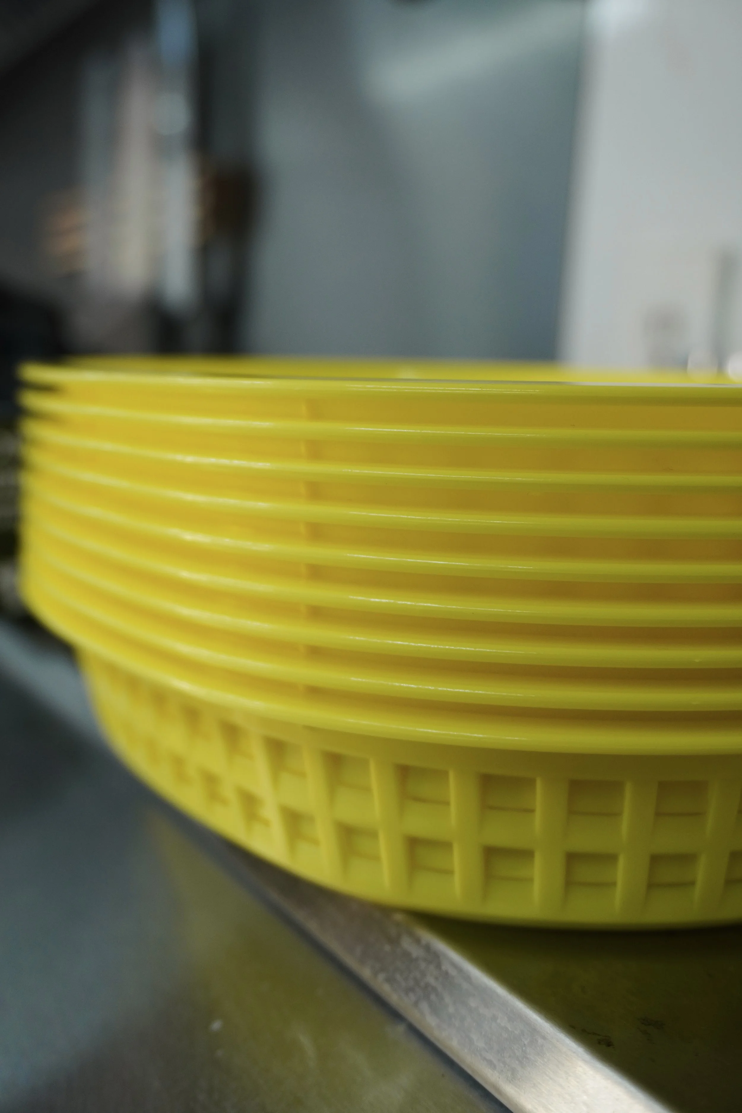 A yellow plastic basket on a stainless steel counter, with a blurred background.