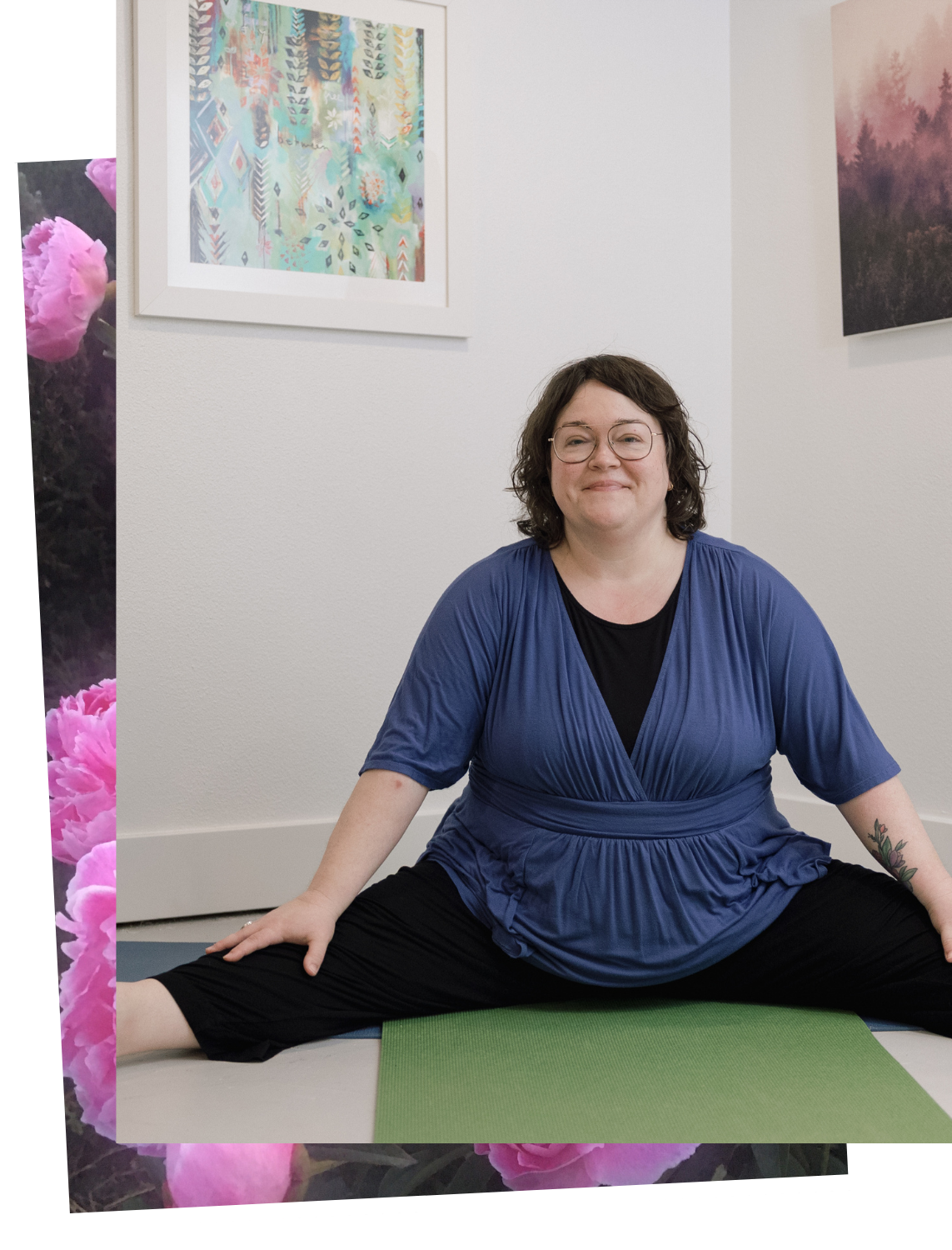 A woman practicing yoga in a seated wide-leg stretch on a green yoga mat in an art gallery with framed paintings on the wall.