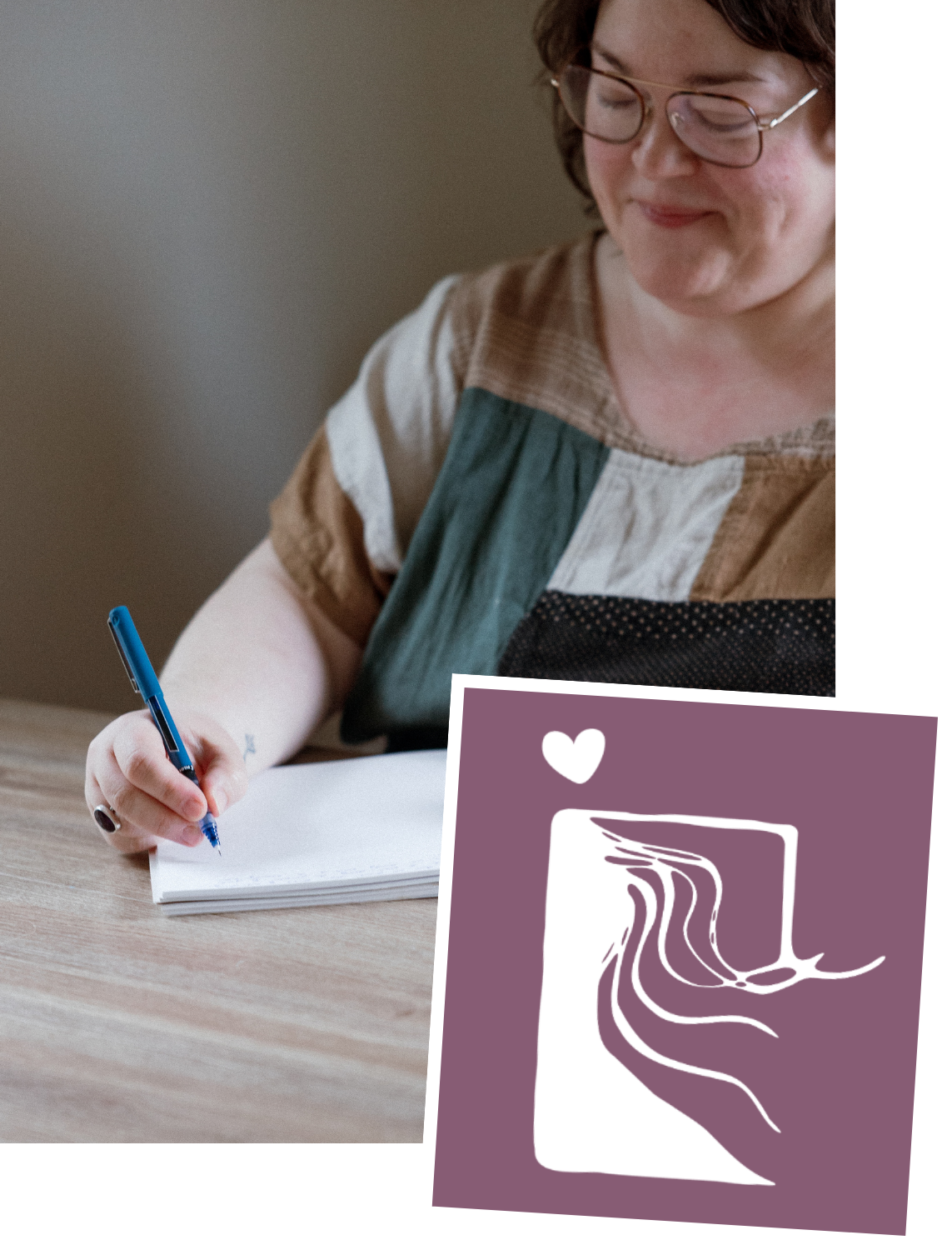 A woman with glasses writing in a notebook, with a purple card featuring a white abstract design and a heart symbol sitting on the table.