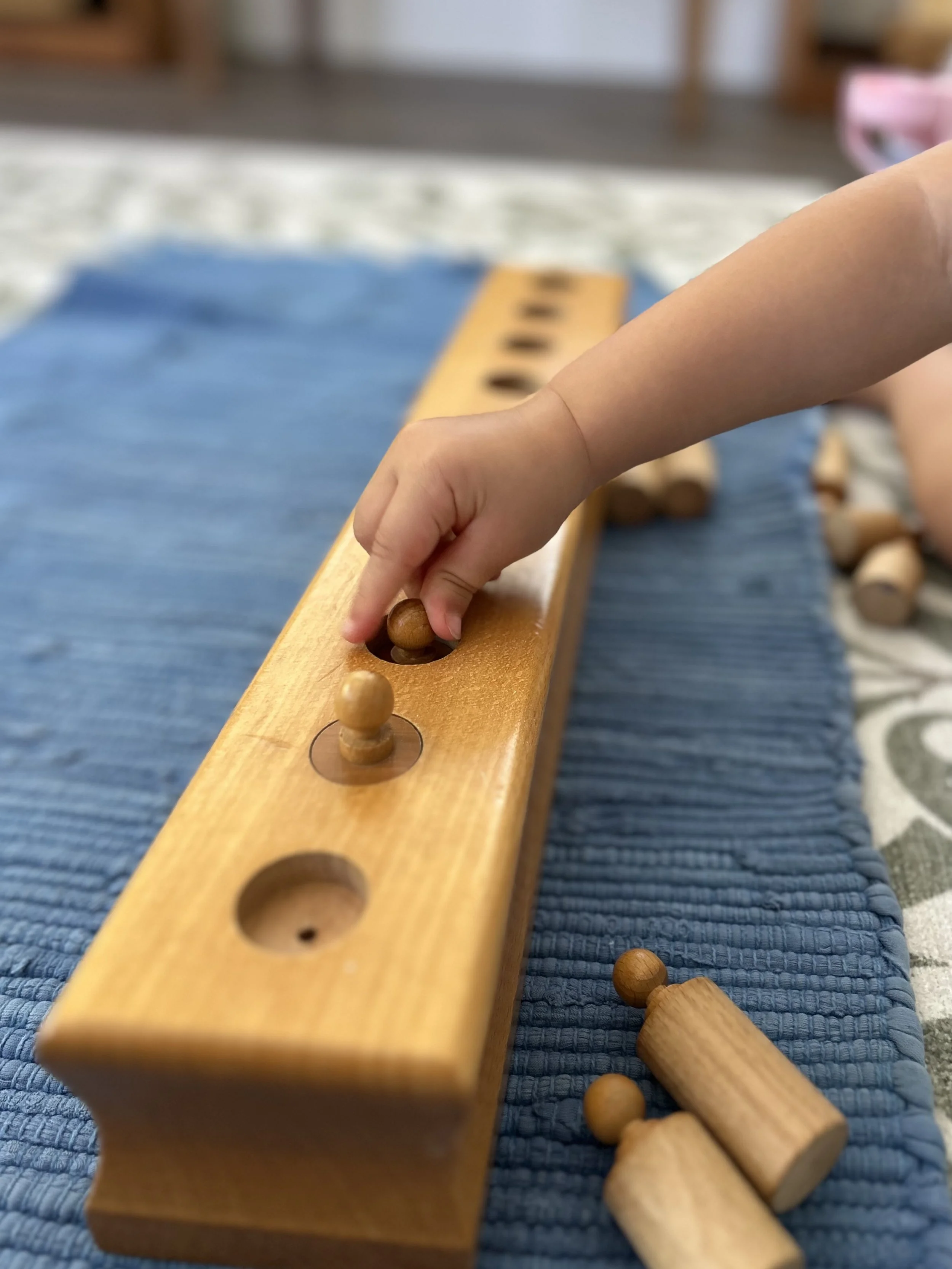 Child practices fine motor skills by matching pegs to their corresponding openings.