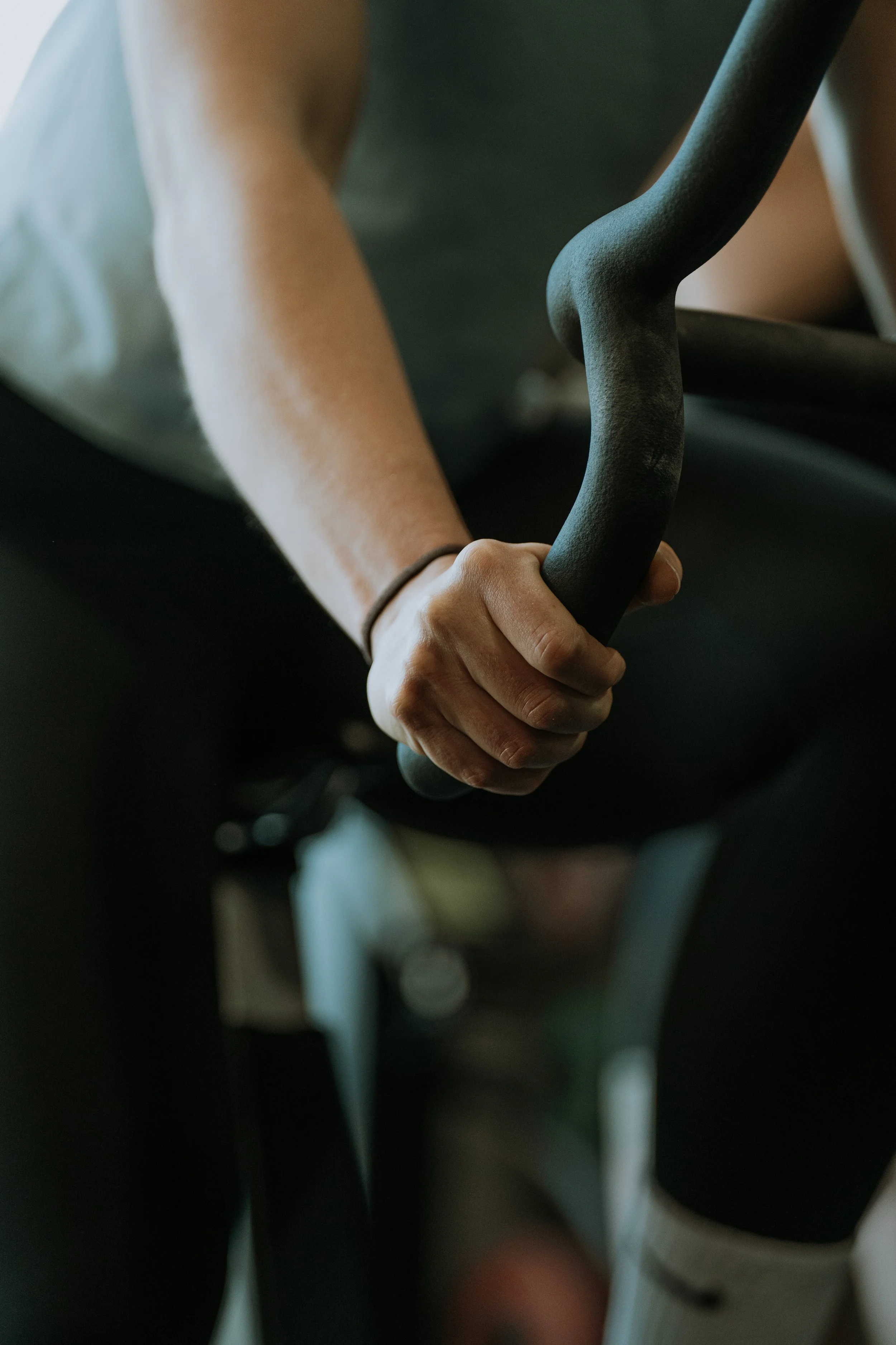 A close-up of a person's hand gripping a black handle of a piece of exercise equipment or machinery.