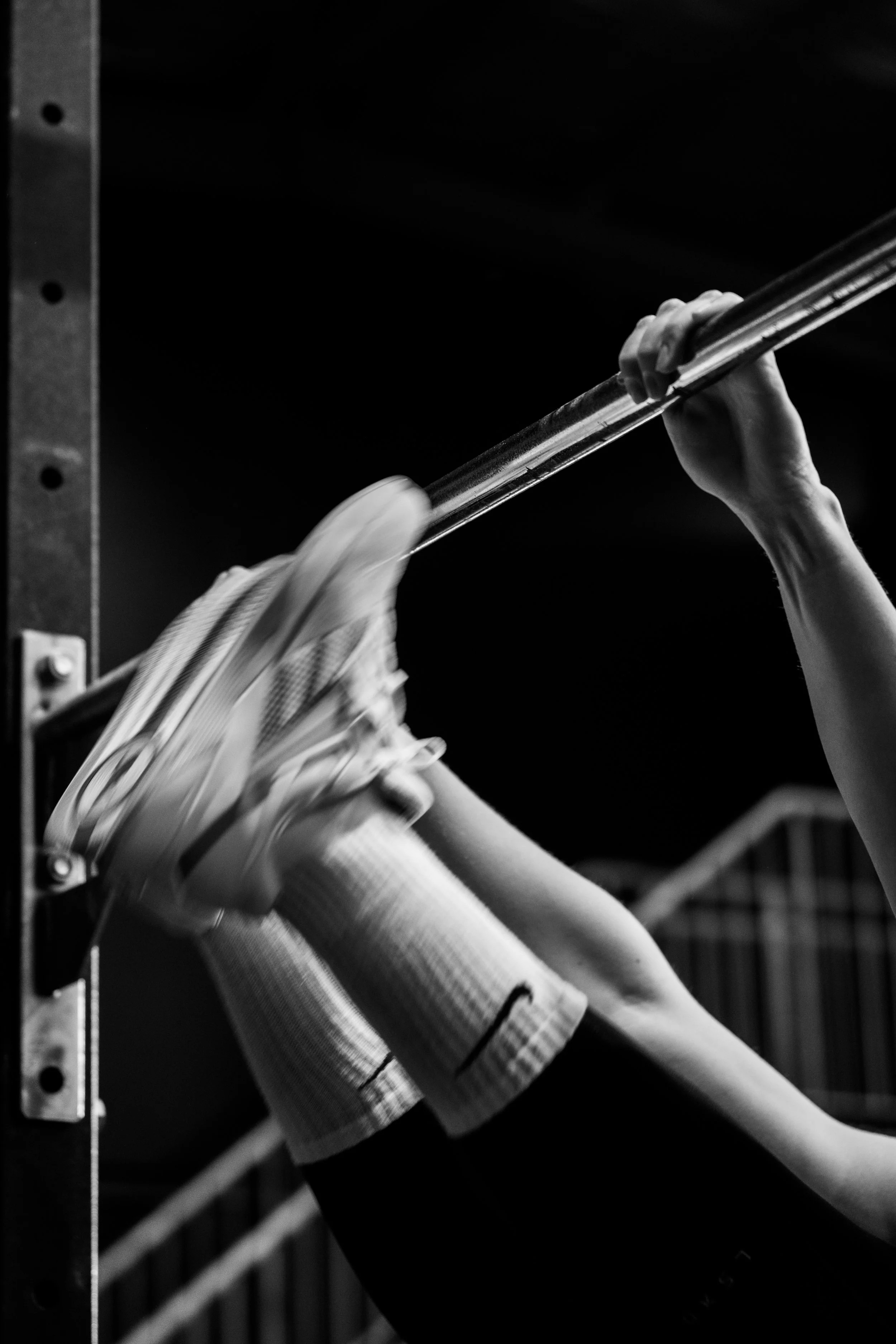 Person performing a pull-up exercise using a pull-up bar in a fitness gym.