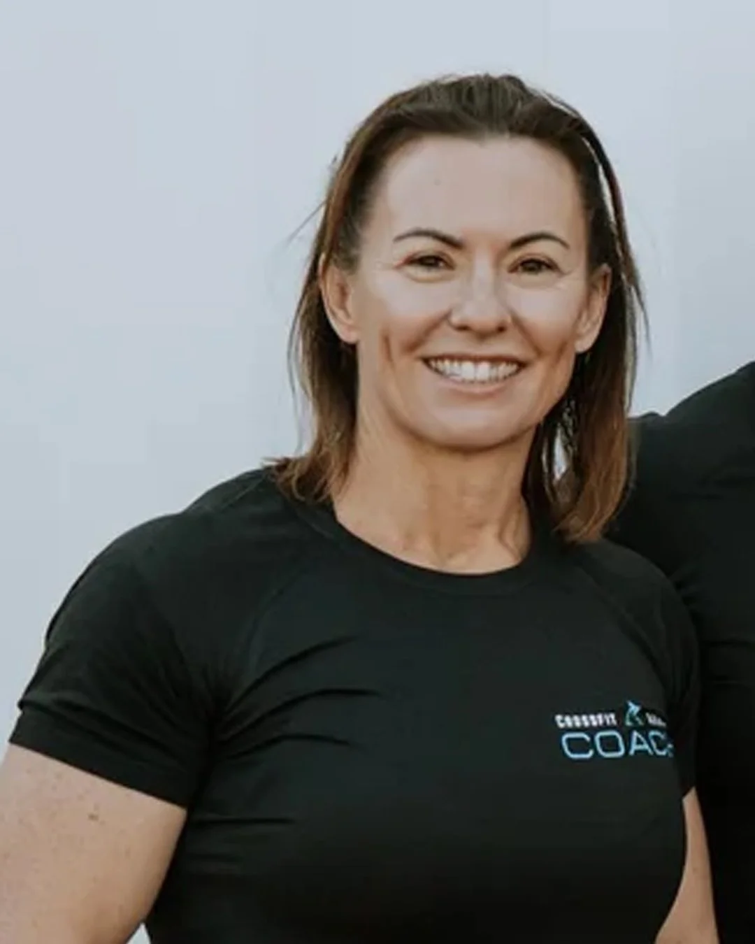Smiling woman with shoulder-length brown hair wearing a black athletic shirt.