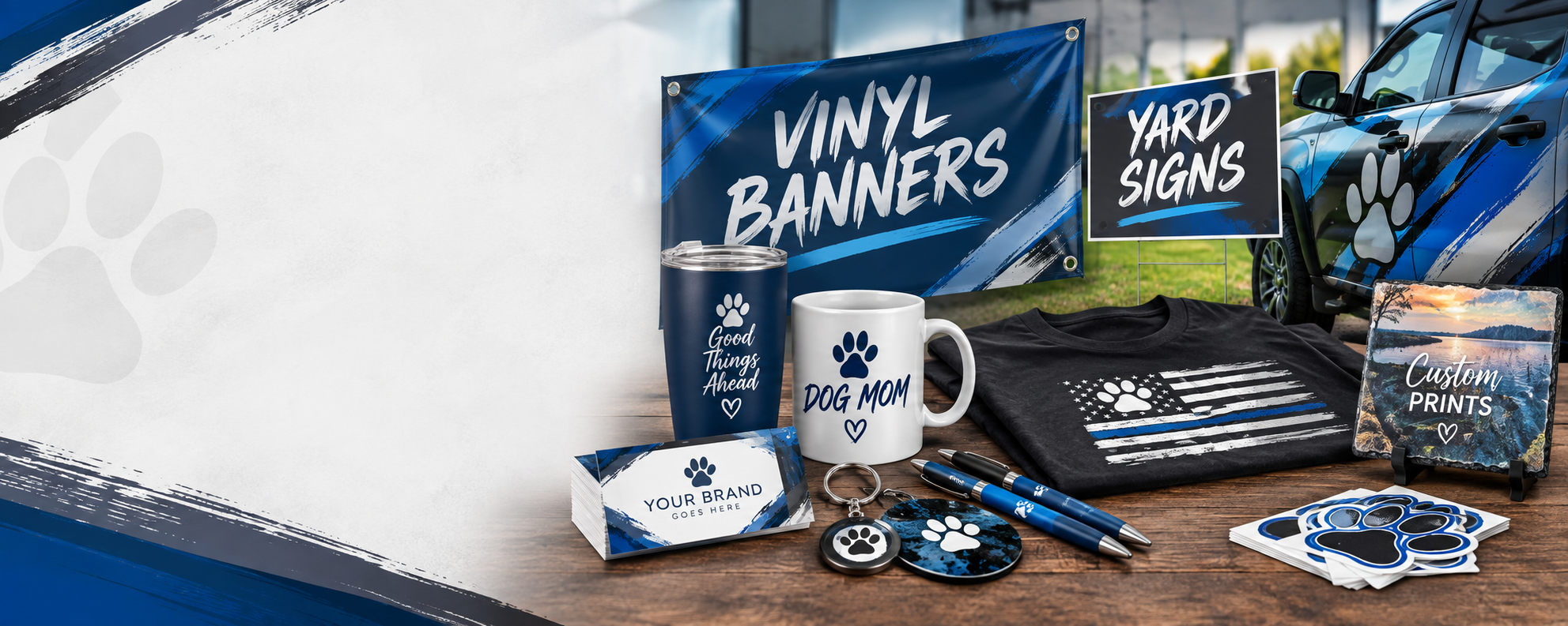 Dog-themed merchandise display at a market booth, including banners, mugs, clothing, stickers, and prints with paw prints, American flag, and nature scenes.