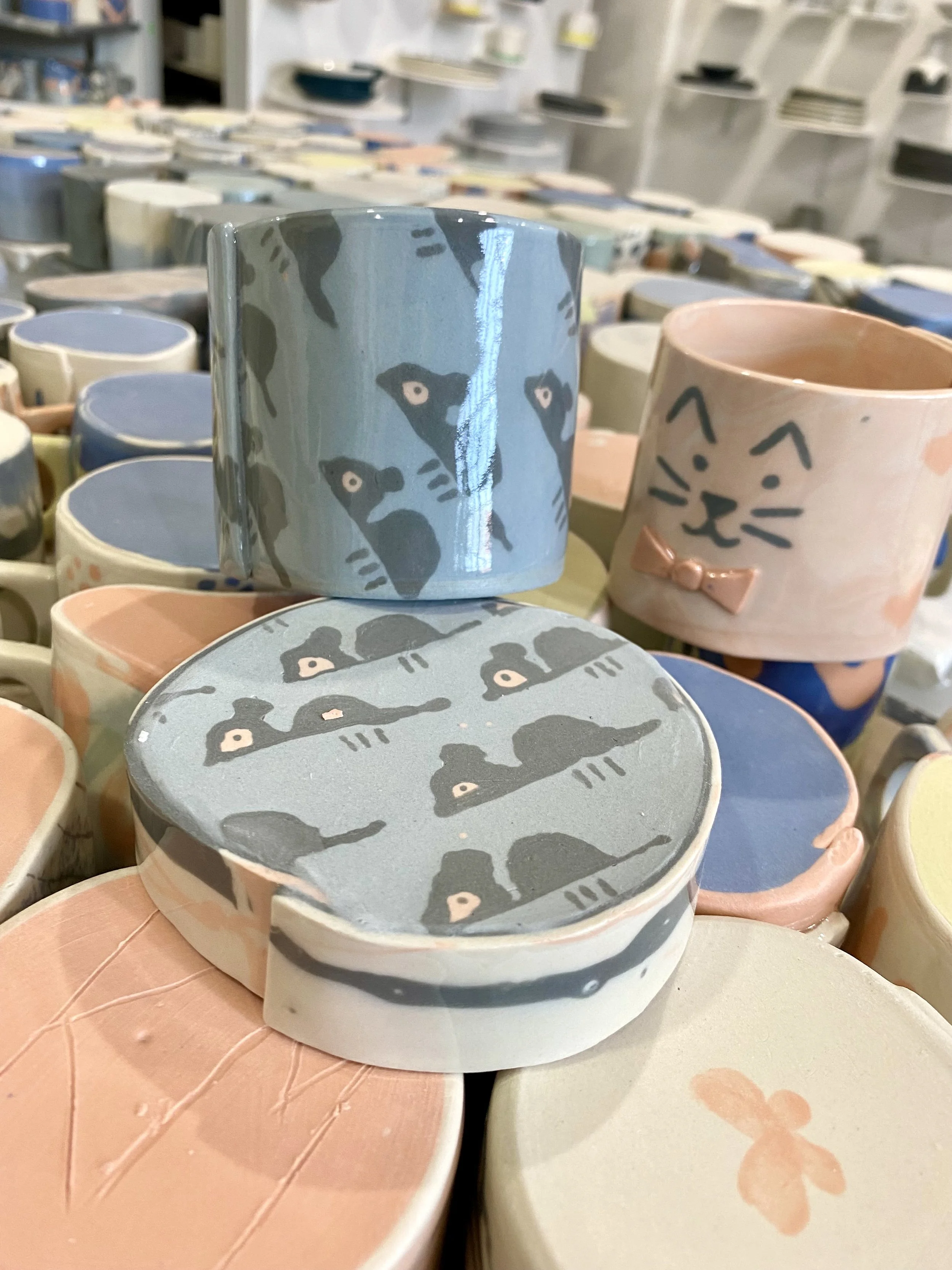 Stacked colorful cups with animal and butterfly designs at a store display.