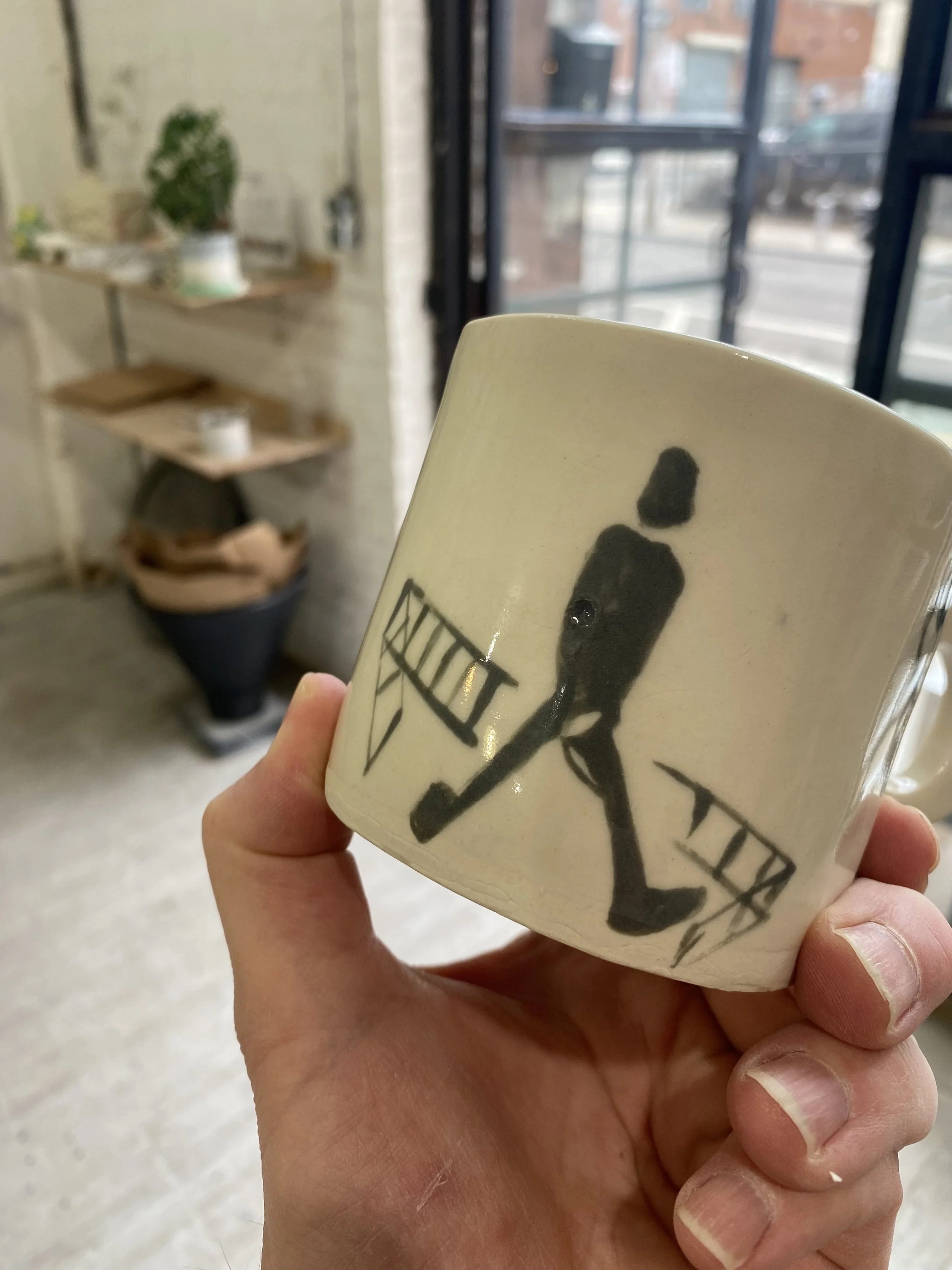 A handmade ceramic mug with a black silhouette of a person walking.