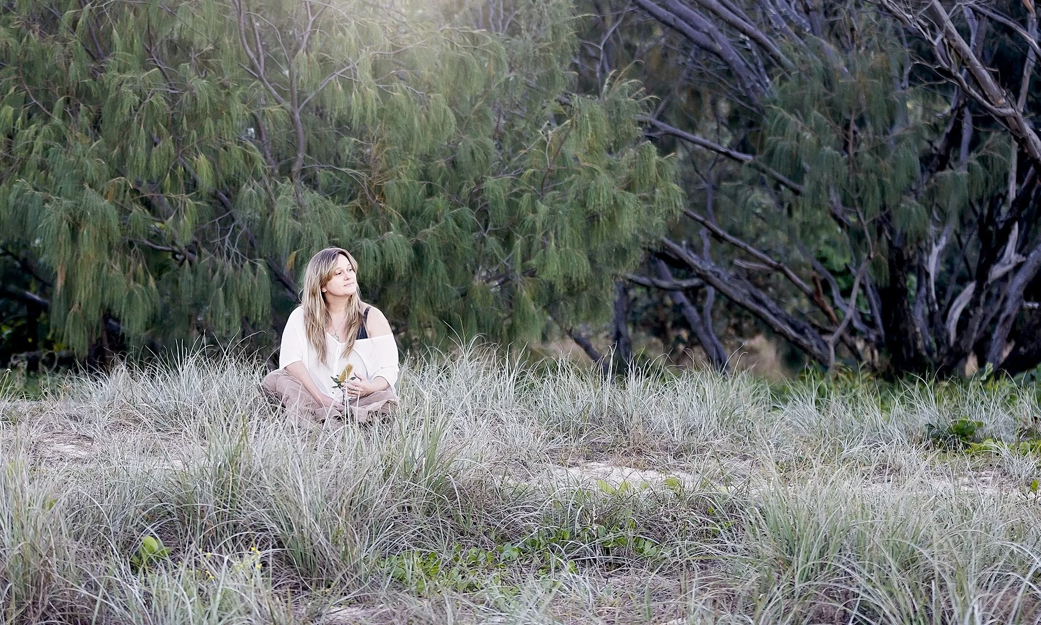 Woman in nature holding a plant — symbolising connection to natural healing, plant medicine, and wellbeing.