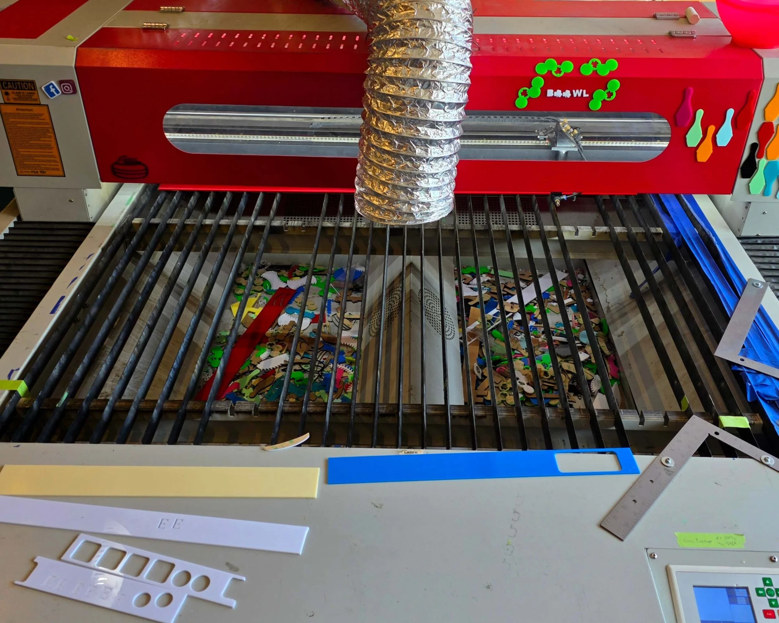 shows the growing acrylic waste in the bin under the laser cutting surface