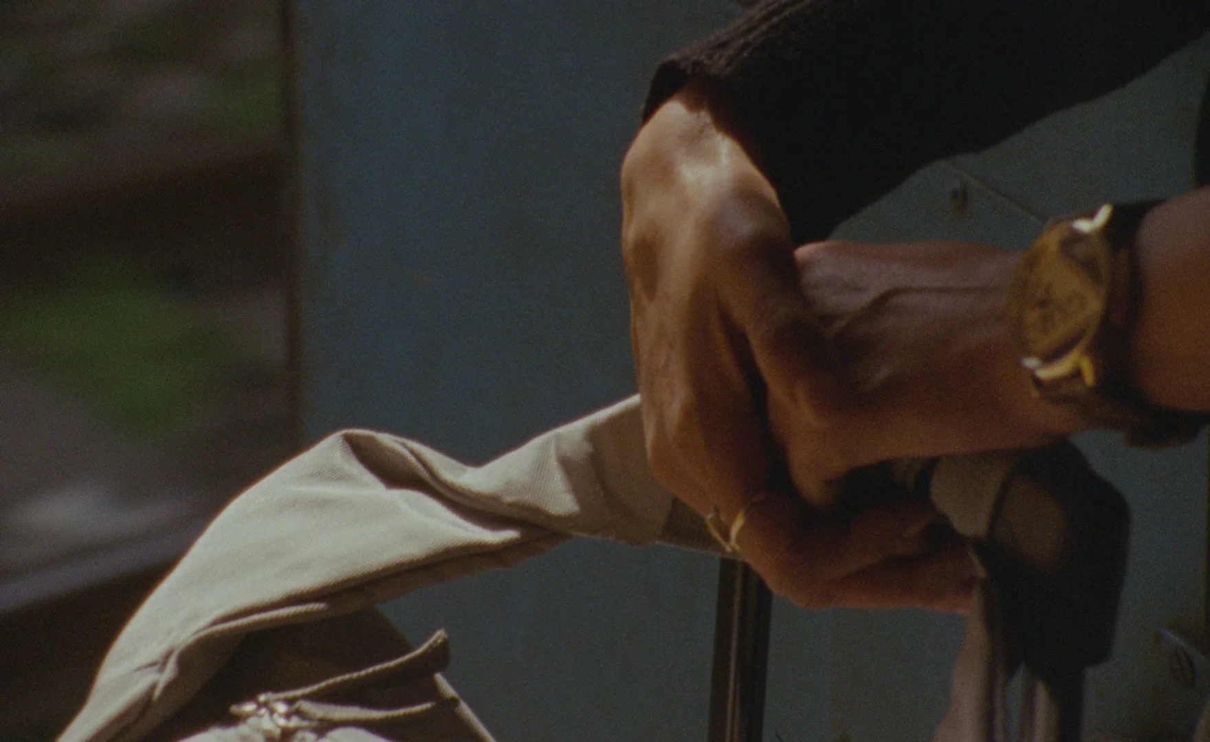 A person engaged with hands on top of each other on a suitcase handle.