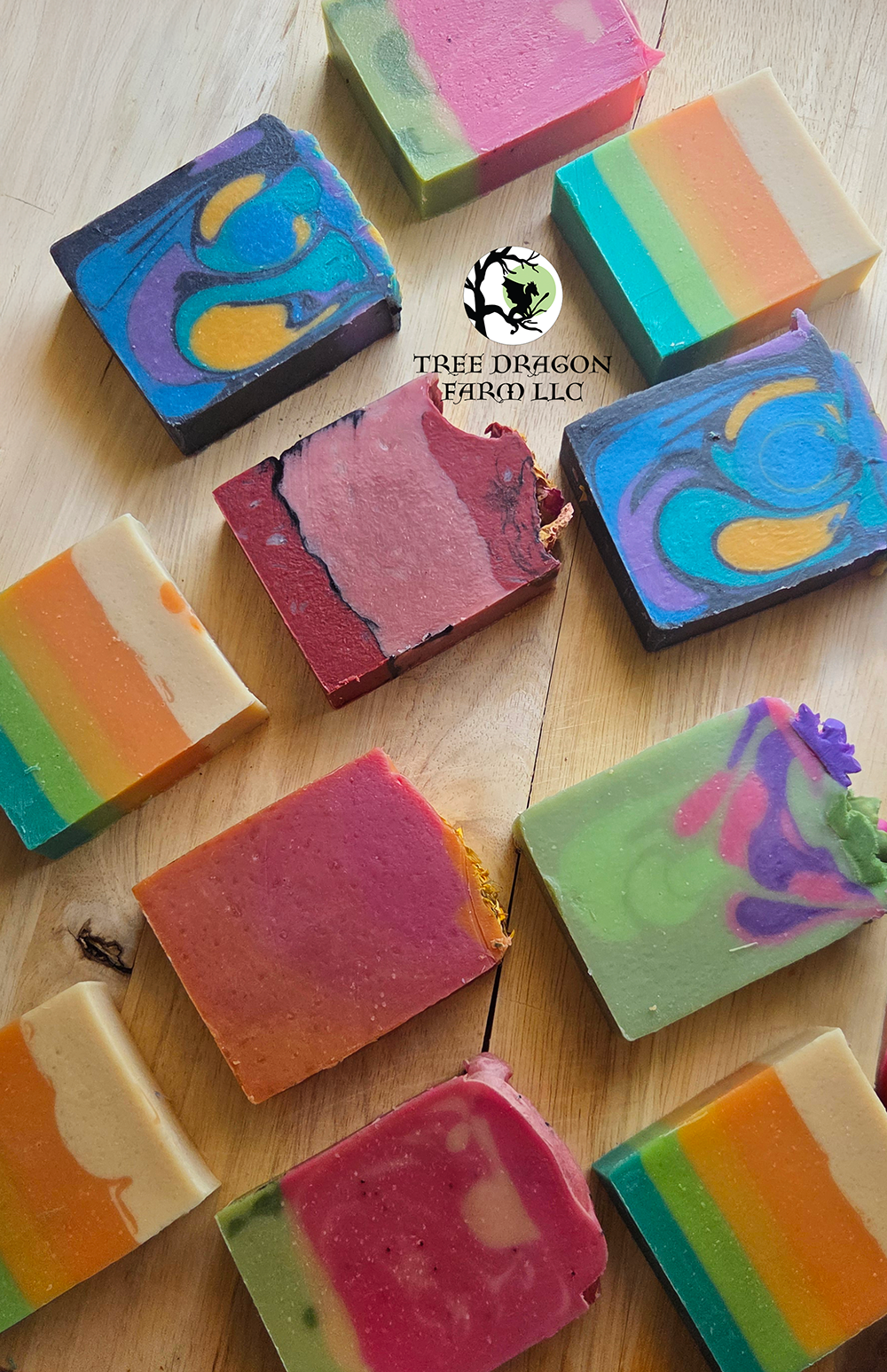 Colorful handmade soaps with various designs and patterns, arranged on a wooden surface, with a logo that says "Tree Dragon Eare LLC" in the center.