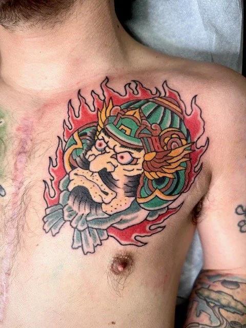 Colorful tattoo of a tiger with a helmet and flames on a person's upper chest.