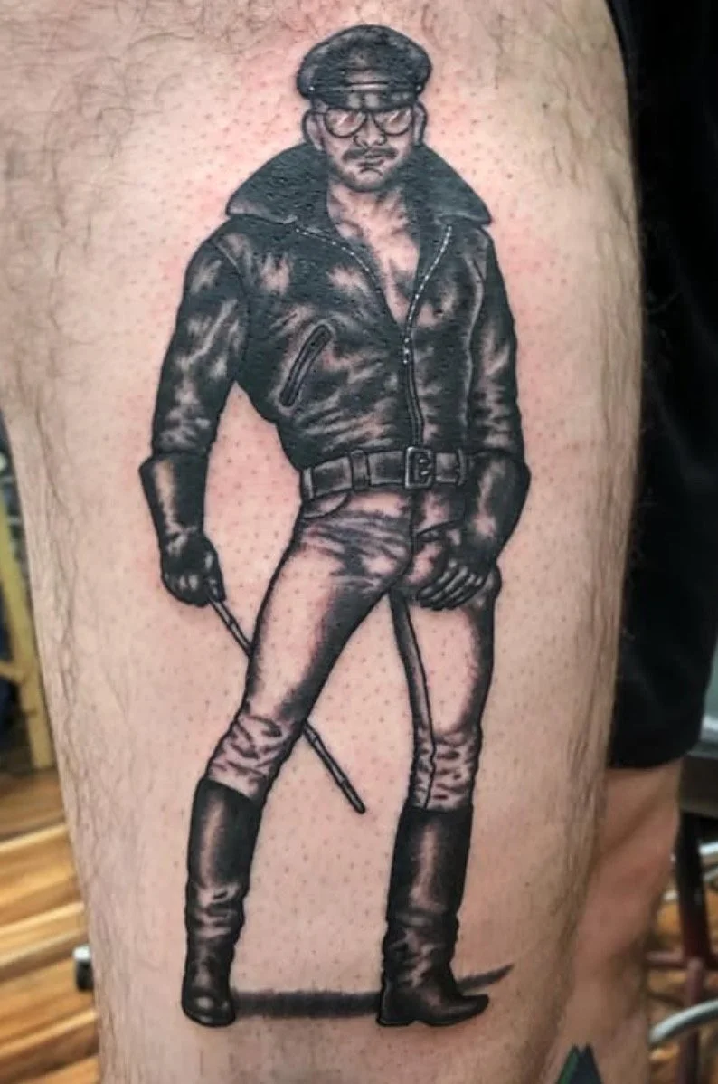 Black and gray tattoo of a man in military or sheriff style uniform with a hat, glasses, coat, pants, and boots, holding a baton.