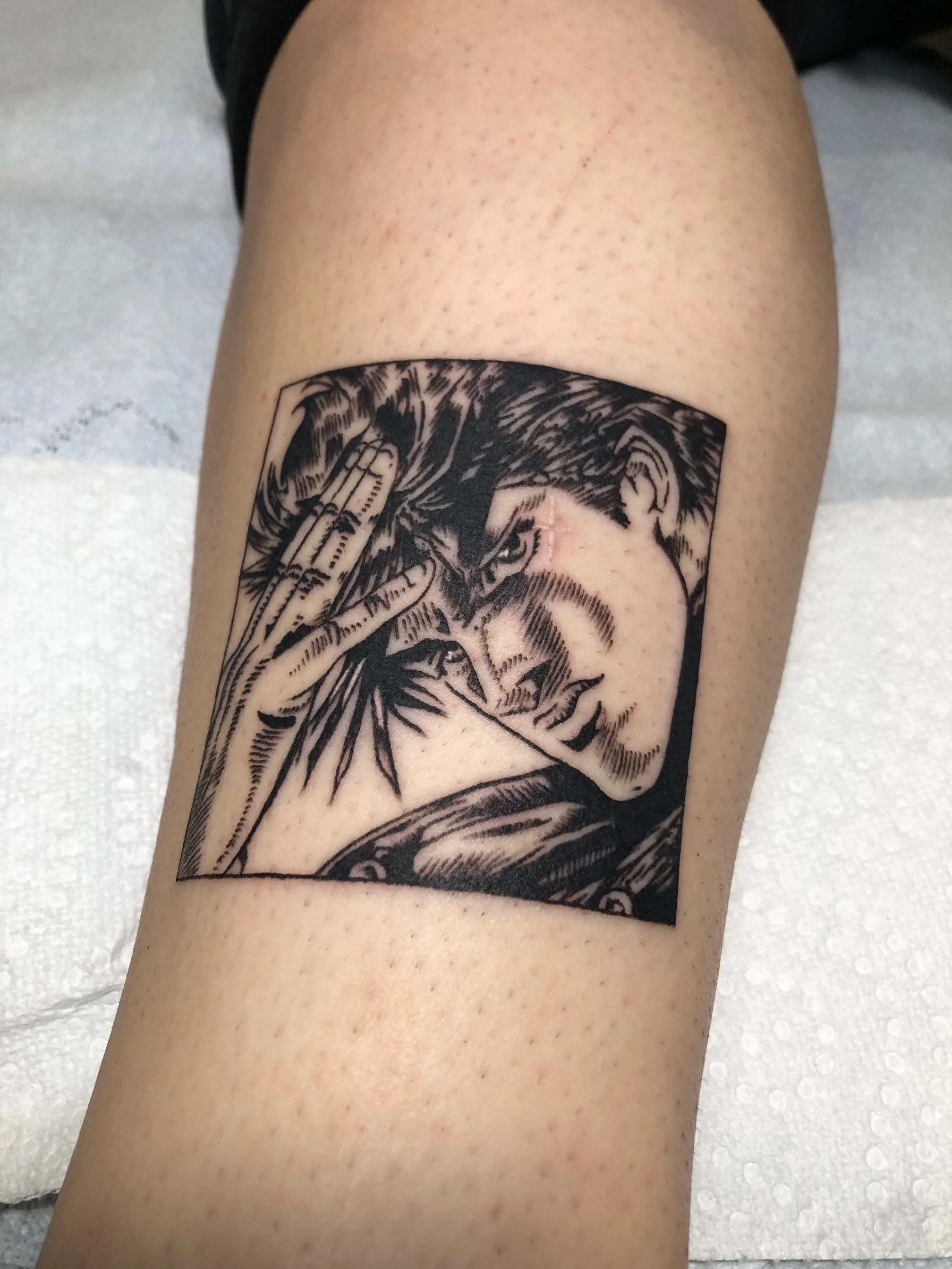 A black and gray tattoo of a woman with short hair in a comic book style, making a peace sign near her temple.