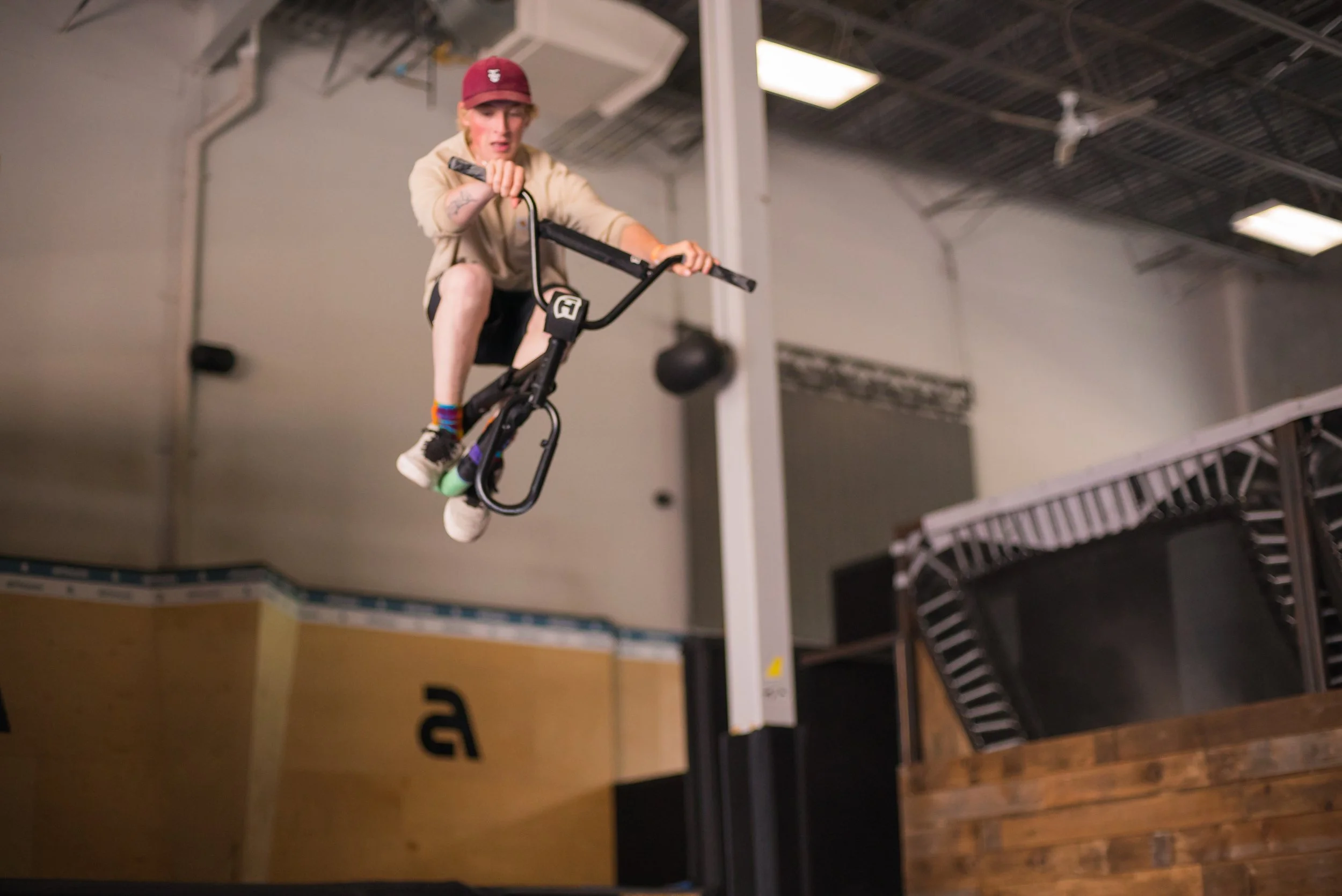 Person performing a jump on a BMX bike inside an indoor skatepark.