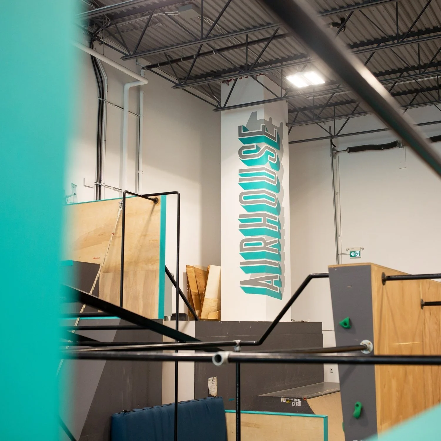 Indoor climbing gym with the text 'ALTITUDE' painted on a large vertical column.