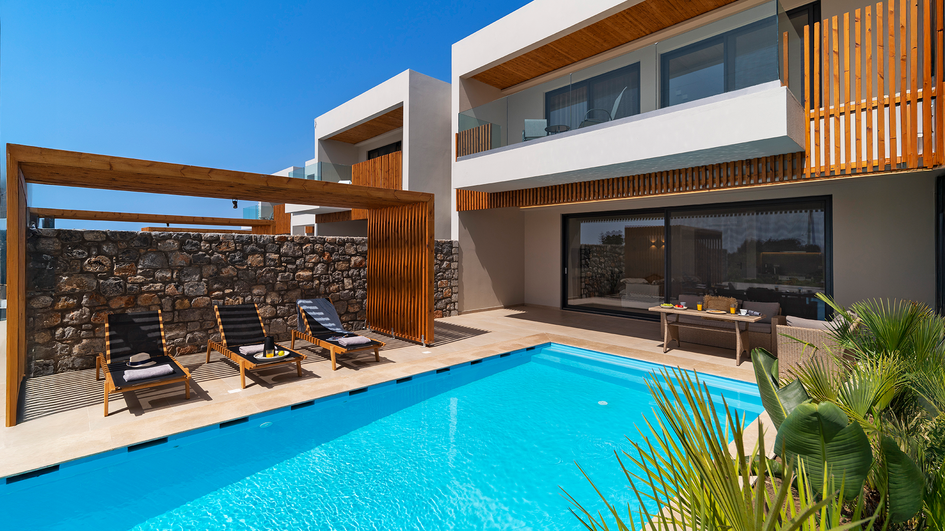 Rhodes Sea View Villa with a swimming pool, poolside lounge chairs, and outdoor seating area under a clear blue sky.