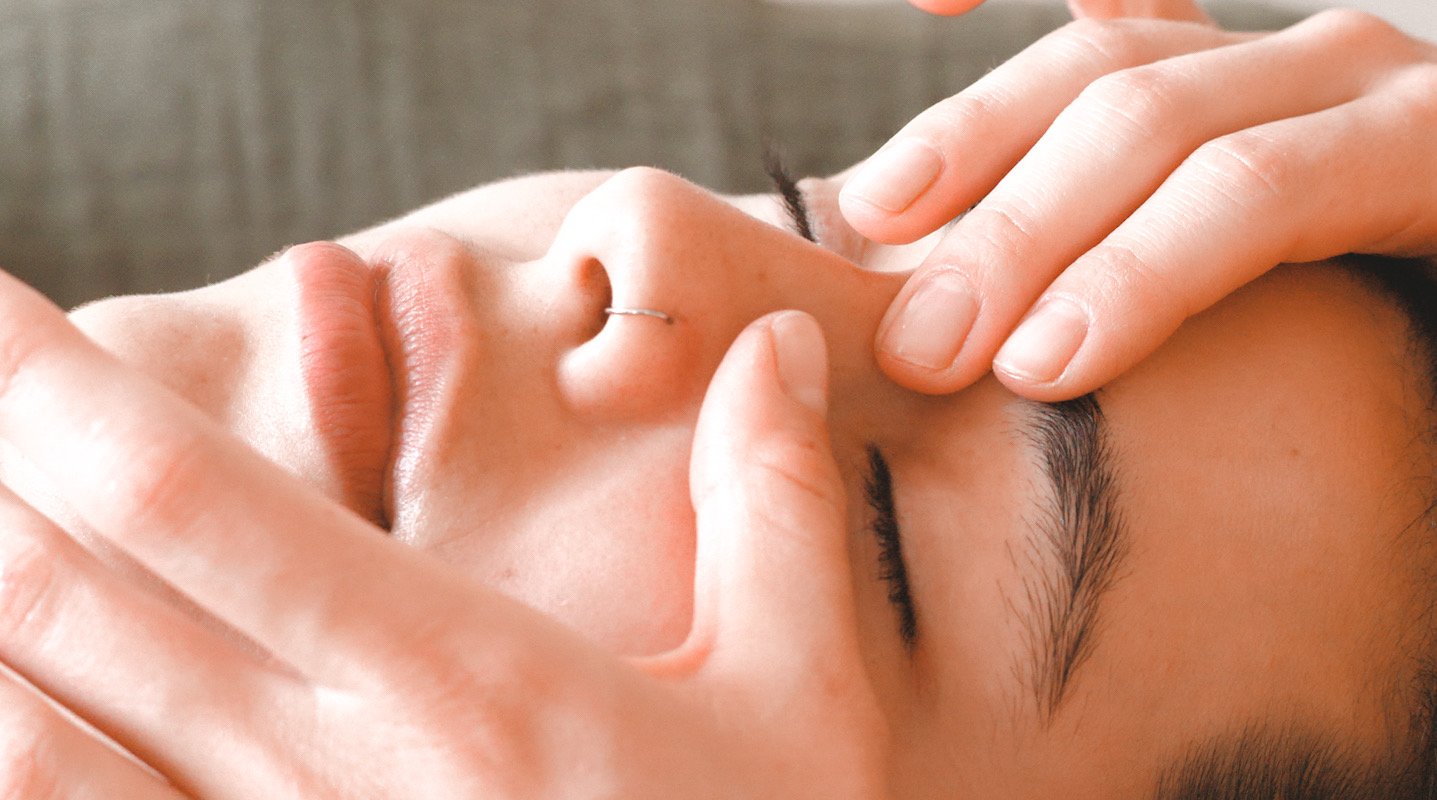 Detailed view of a Kobido therapist’s hands gently massaging the face, showcasing traditional Japanese facial massage techniques in Berlin