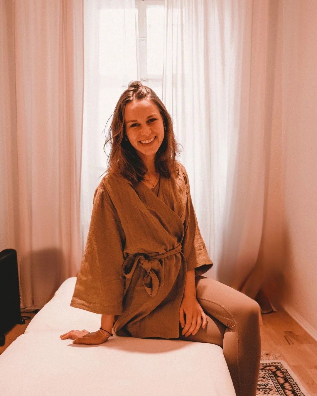 Kobido therapist Marta in Berlin seated on a massage table, offering traditional Japanese facial massage in a serene studio setting