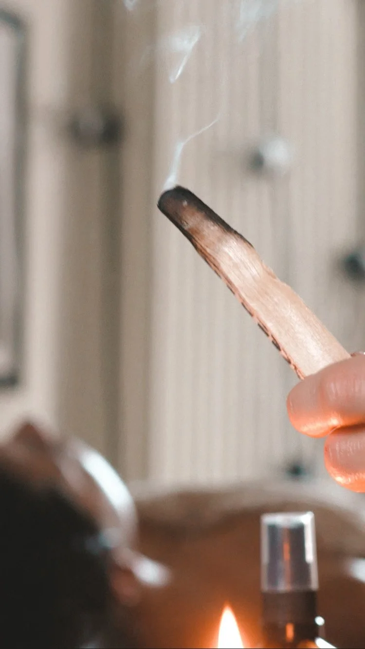 Hand holding a lit palo santo stick with gentle smoke rising – calming ritual at Kobido Berlin