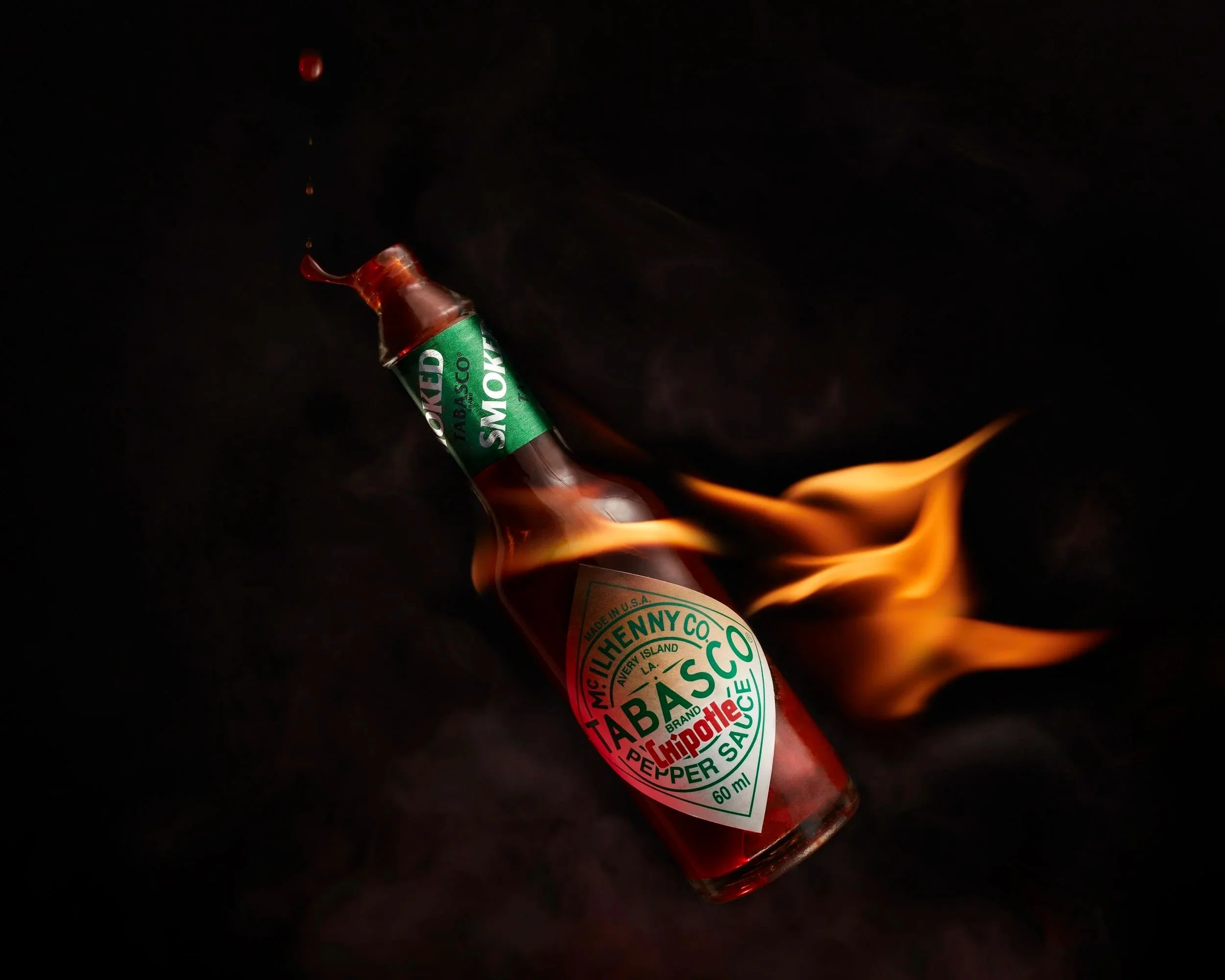 A bottle of Tabasco hot sauce with flames and liquid dripping from the top. by jonny mcgilloway photography chester uk