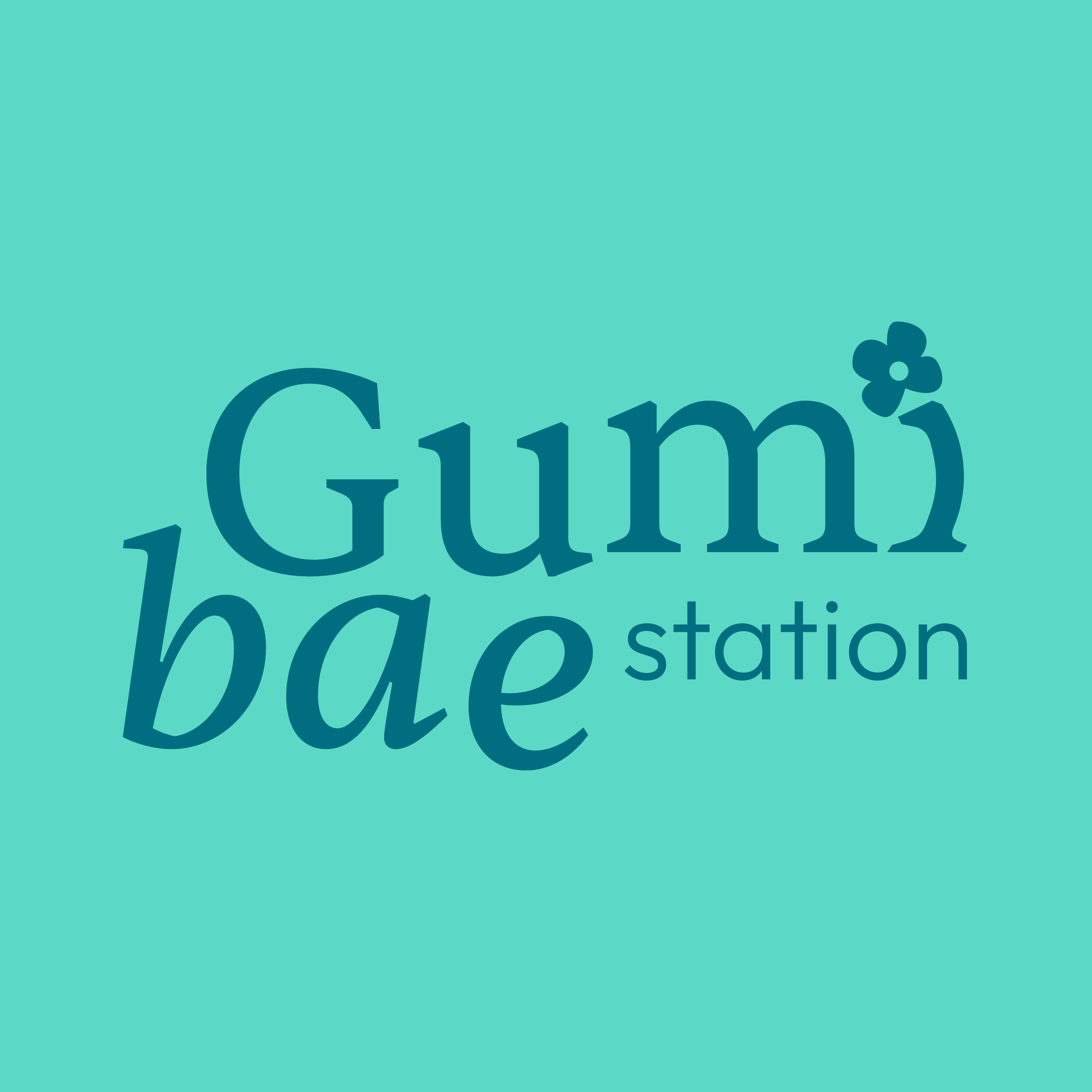 Logo for Gumi Bay Station with stylized text and a small flower icon on a teal background.