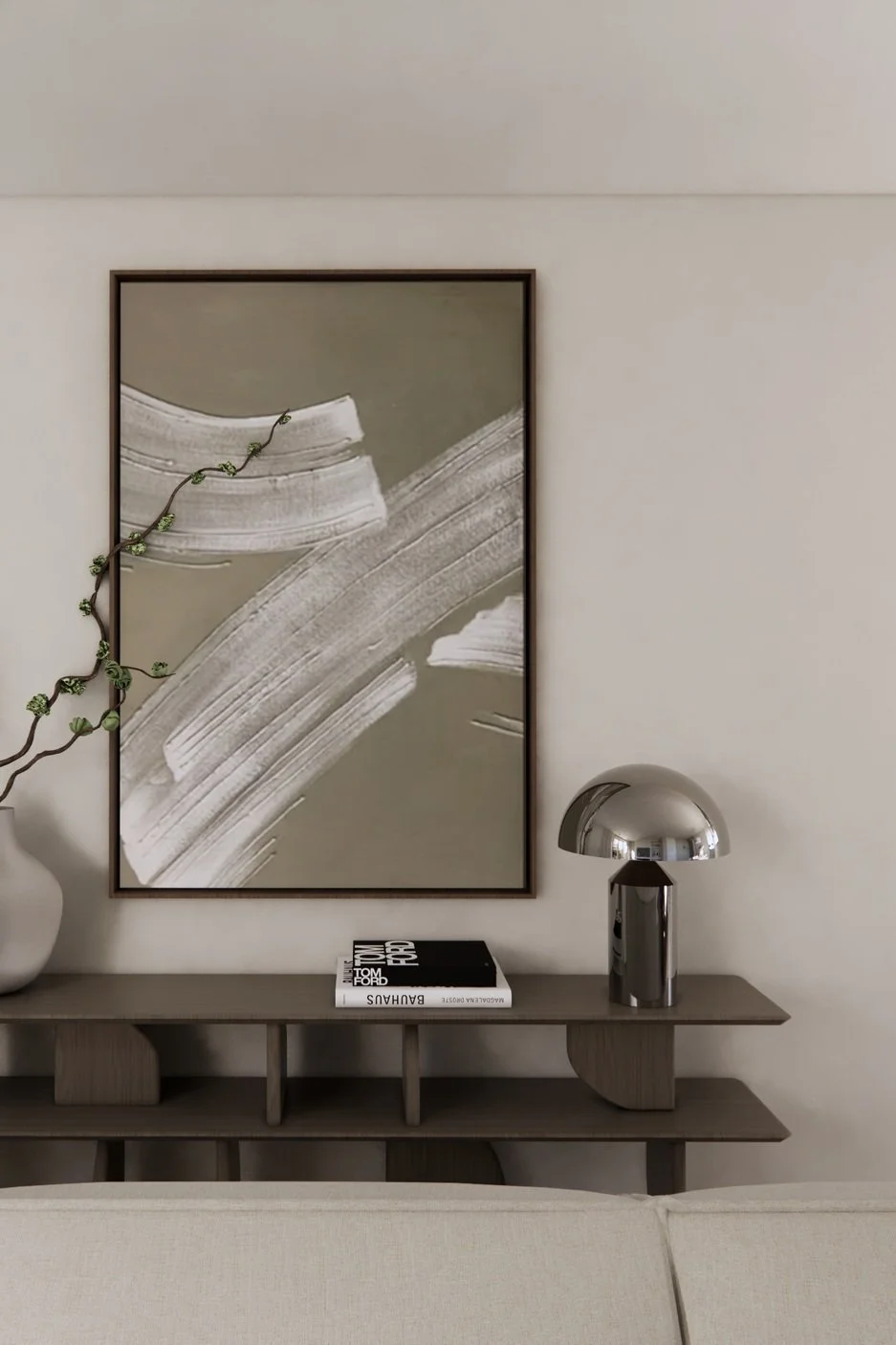 Een grijs houten console met een boek, een moderne metallic lamp, en een wit vaasje met een tak met groene knoppen, hangend naast een grote abstracte kunstwerk met witte en grijze streepen.