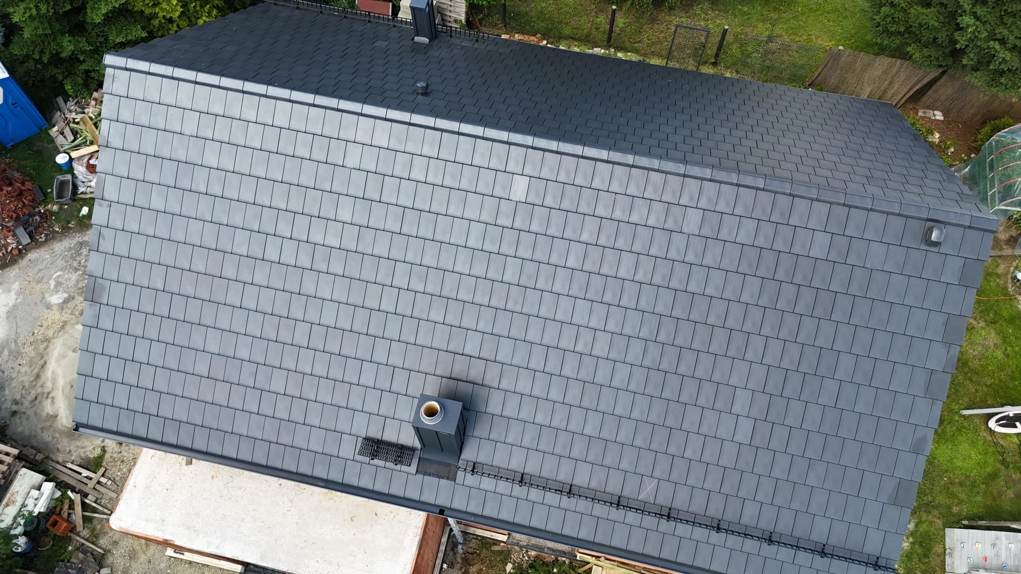Nowoczesny dach domu jednorodzinnego z grafitową dachówką ceramiczną – widok z góry po zakończeniu montażu pokrycia dachowego