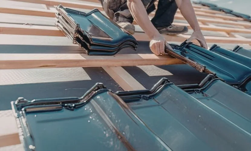 Montaż dachówki ceramicznej na dachu – dekarz układa dachówki na łatach, etap pokrycia dachowego