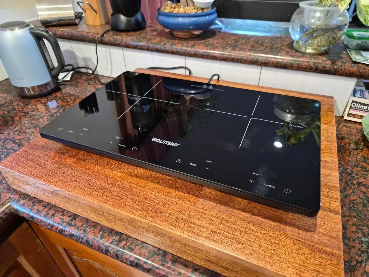 Portable induction hotplace on wooden cover over gas cooktop
