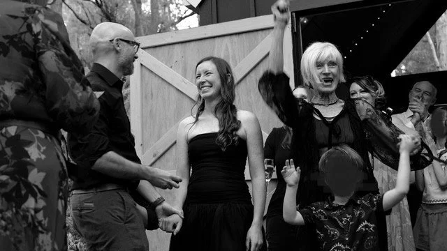 Mother of the bride cheers as the bridal couple look lovingly at each other