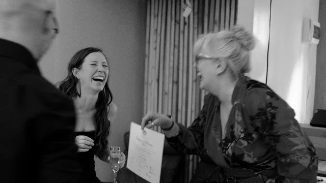 Celebrant Julie is handing the wedding certificate to the  bride. Both are laughing happily at each other