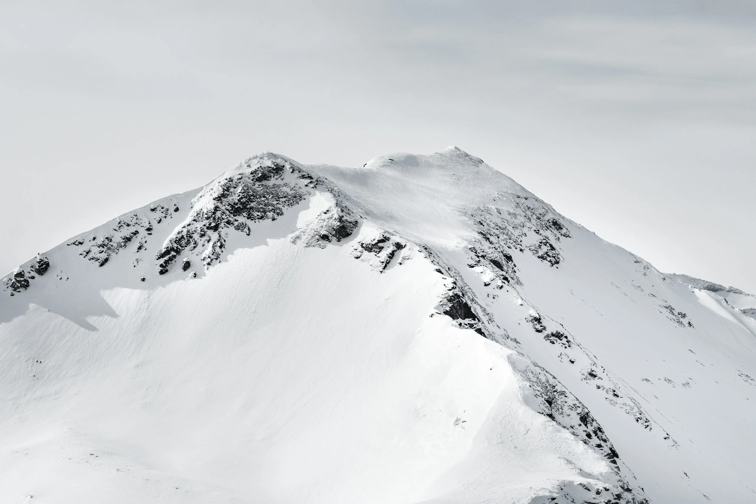 Montagne enneigée avec des rochers visibles sur la façade.