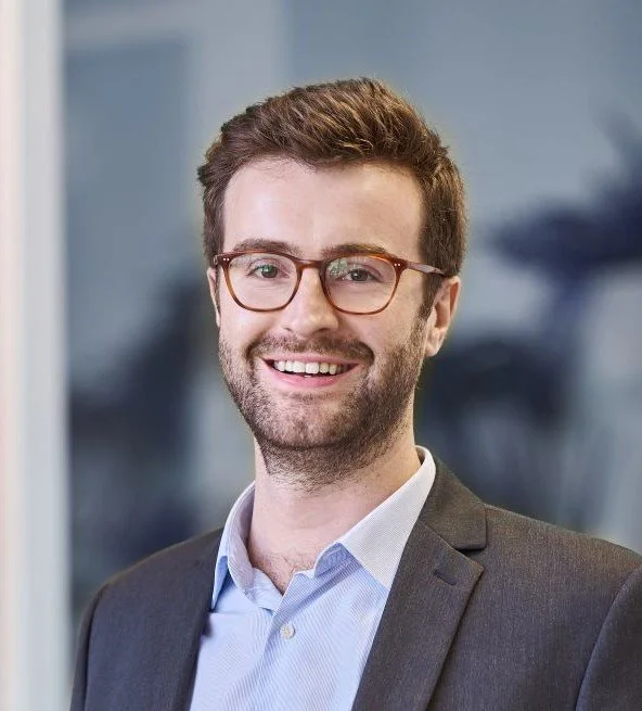 Jean Philippe Saurat, associé Soqio Evaluation, souriant portant des lunettes, en costume, dans un bureau moderne.