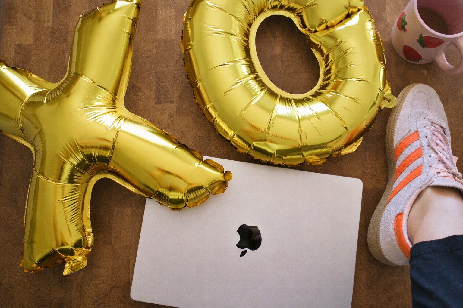 Gold "XO" baloons sit on top of a Mac laptop