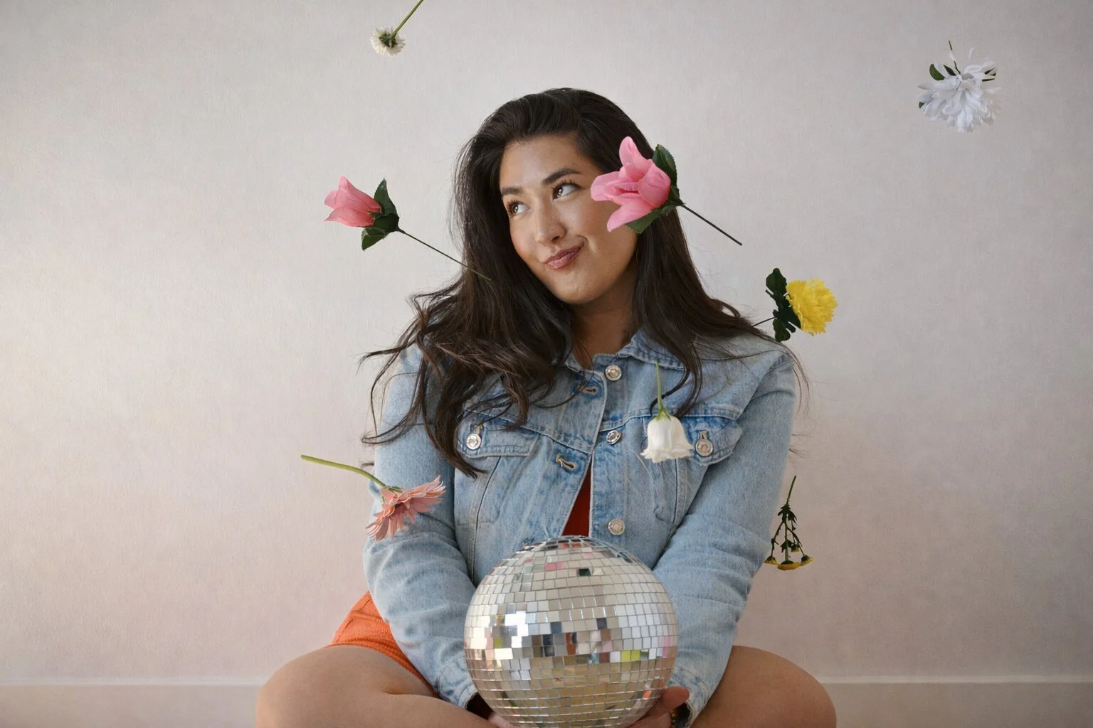A woman with long dark hair sits on the floor holding a diso ball