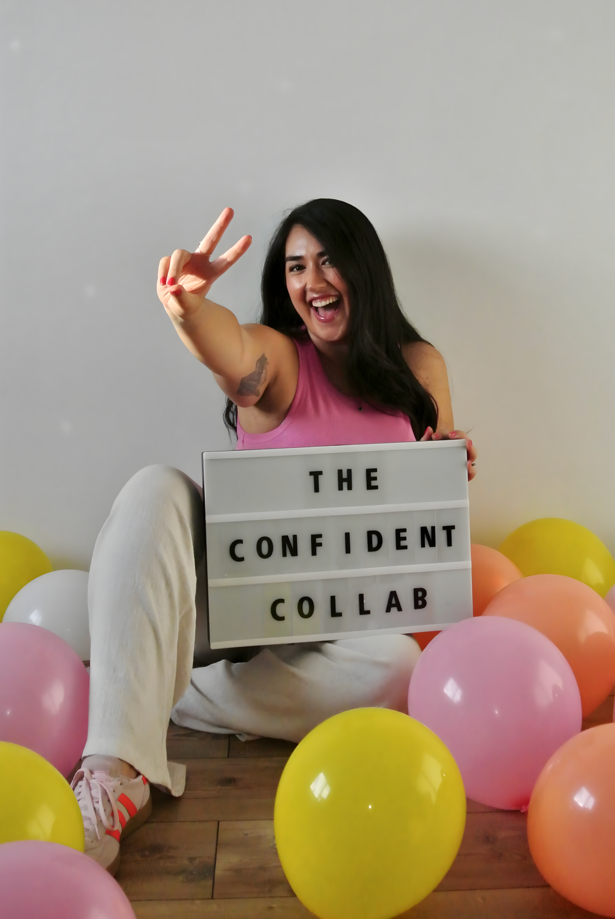 Photo of Ariel De La Mora and a sign with "The Confident Collab"