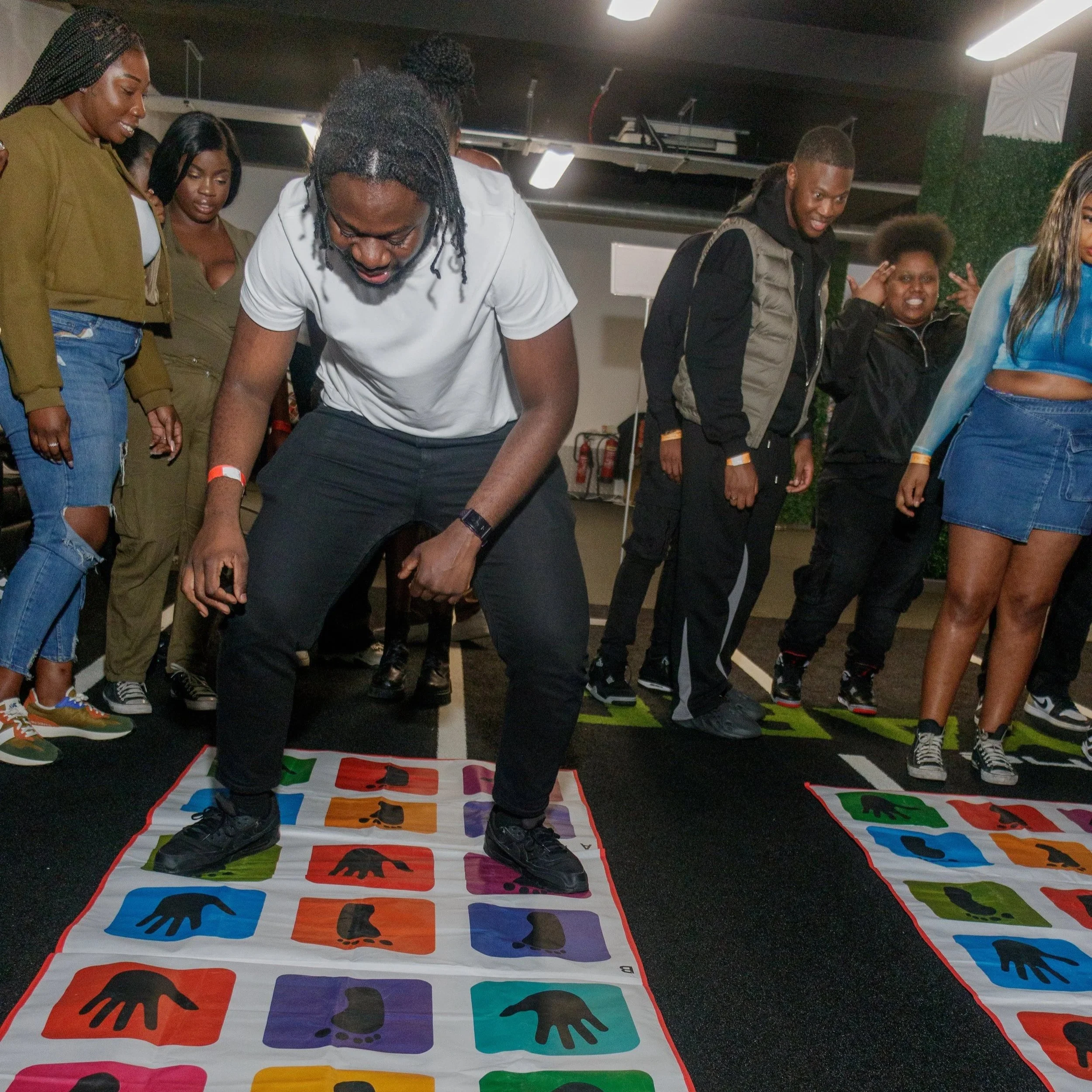 People playing Twister on colorful mats in an indoor setting