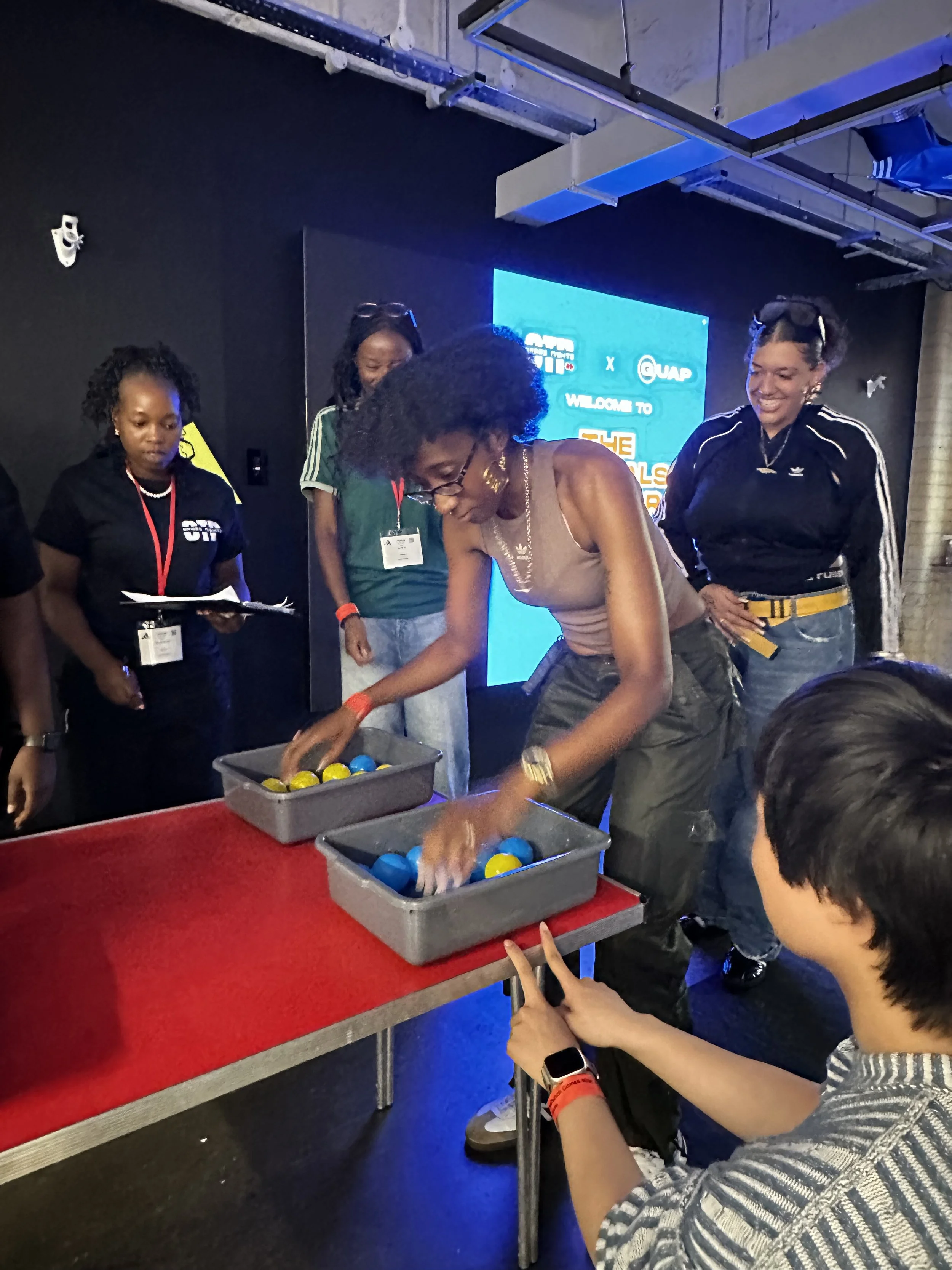 A group of women and children participating in a game or activity involving colored balls at an event or conference.
