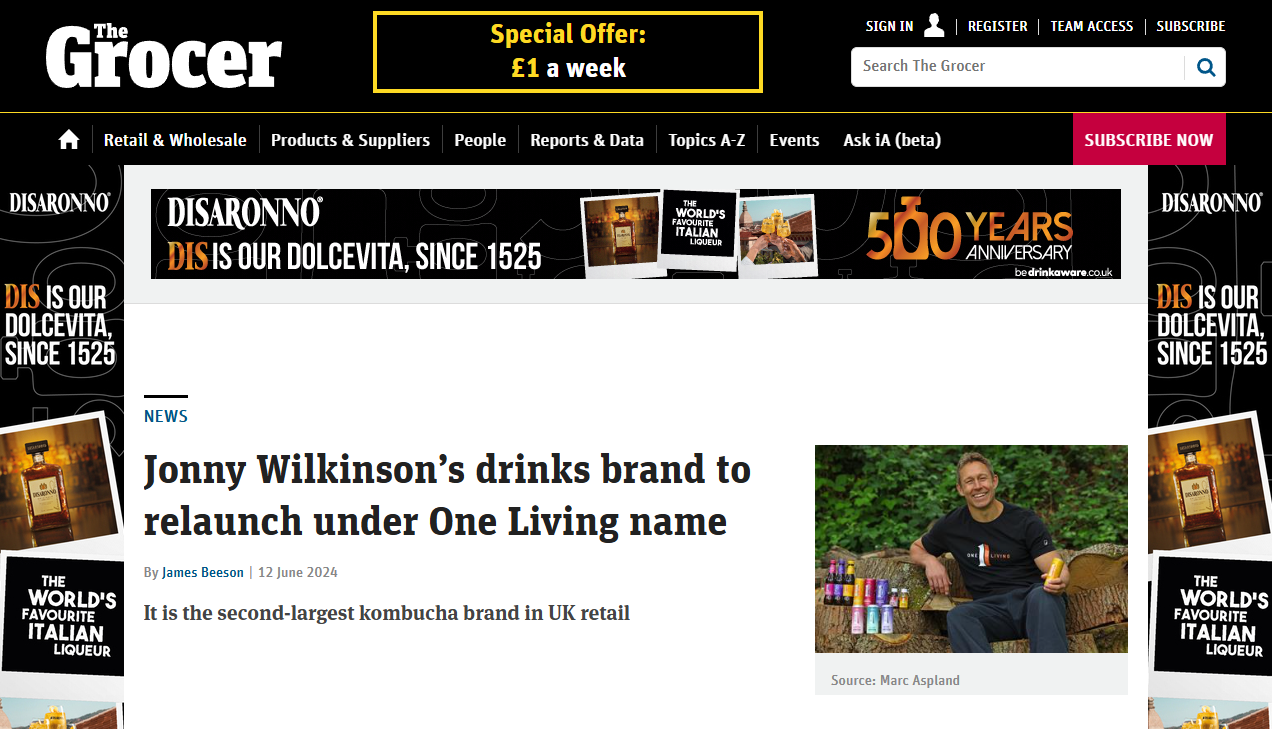 Screenshot of The Grocer news website with an article about Jonny Wilkinson's drinks brand relaunch under One Living, featuring a photo of Jonny Wilkinson sitting on a bench outdoors, smiling, next to bottles of beverages.
