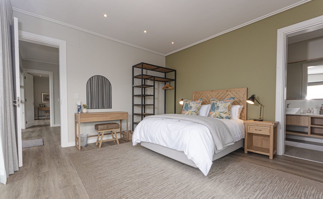 Main bedroom with a large bed, nightstand, open closet, vanity with mirror, and an ensuite bathroom.