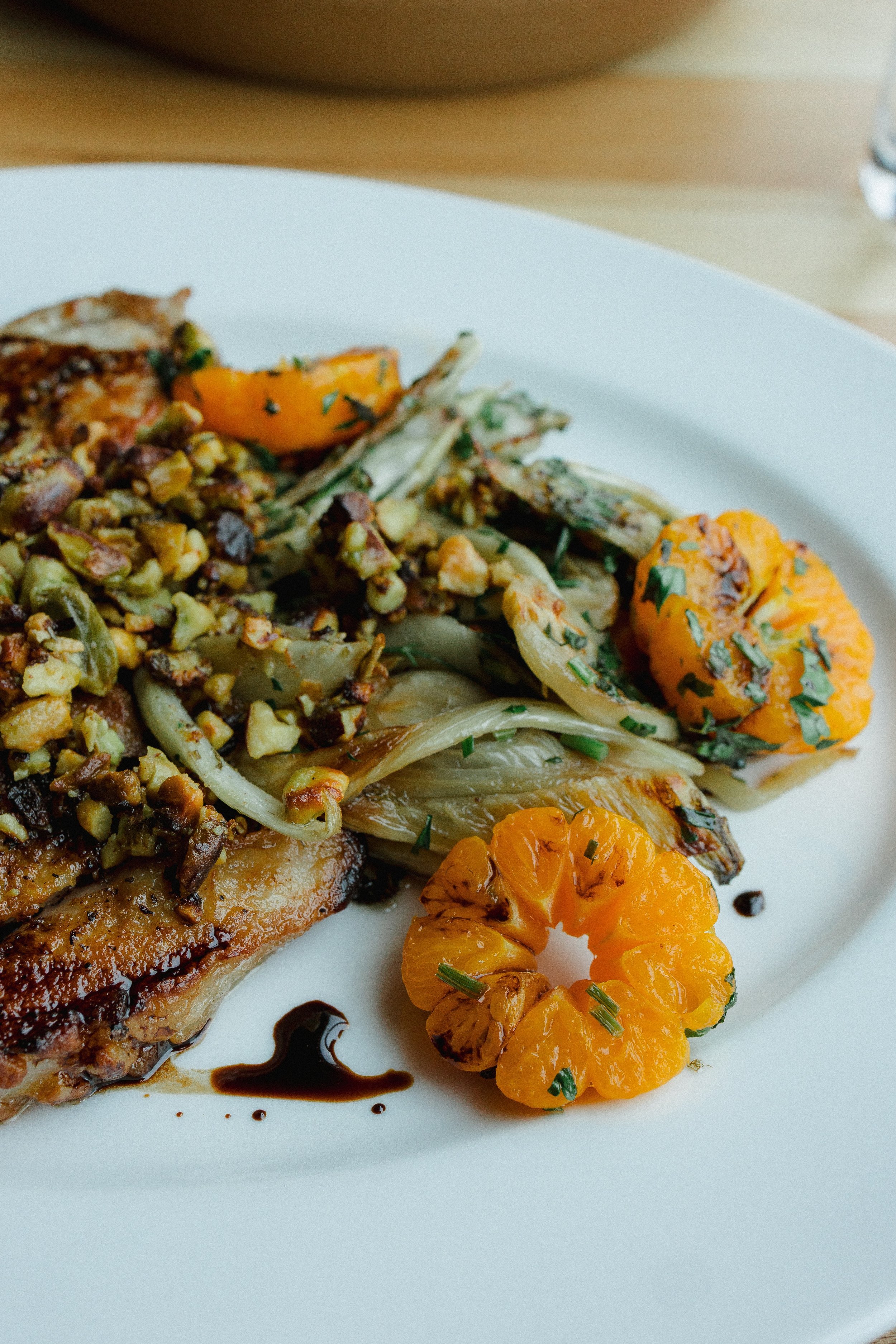 Plate with roasted chicken, roasted sweet potatoes with herbs, caramelized onions, and chopped greens, garnished with balsamic glaze