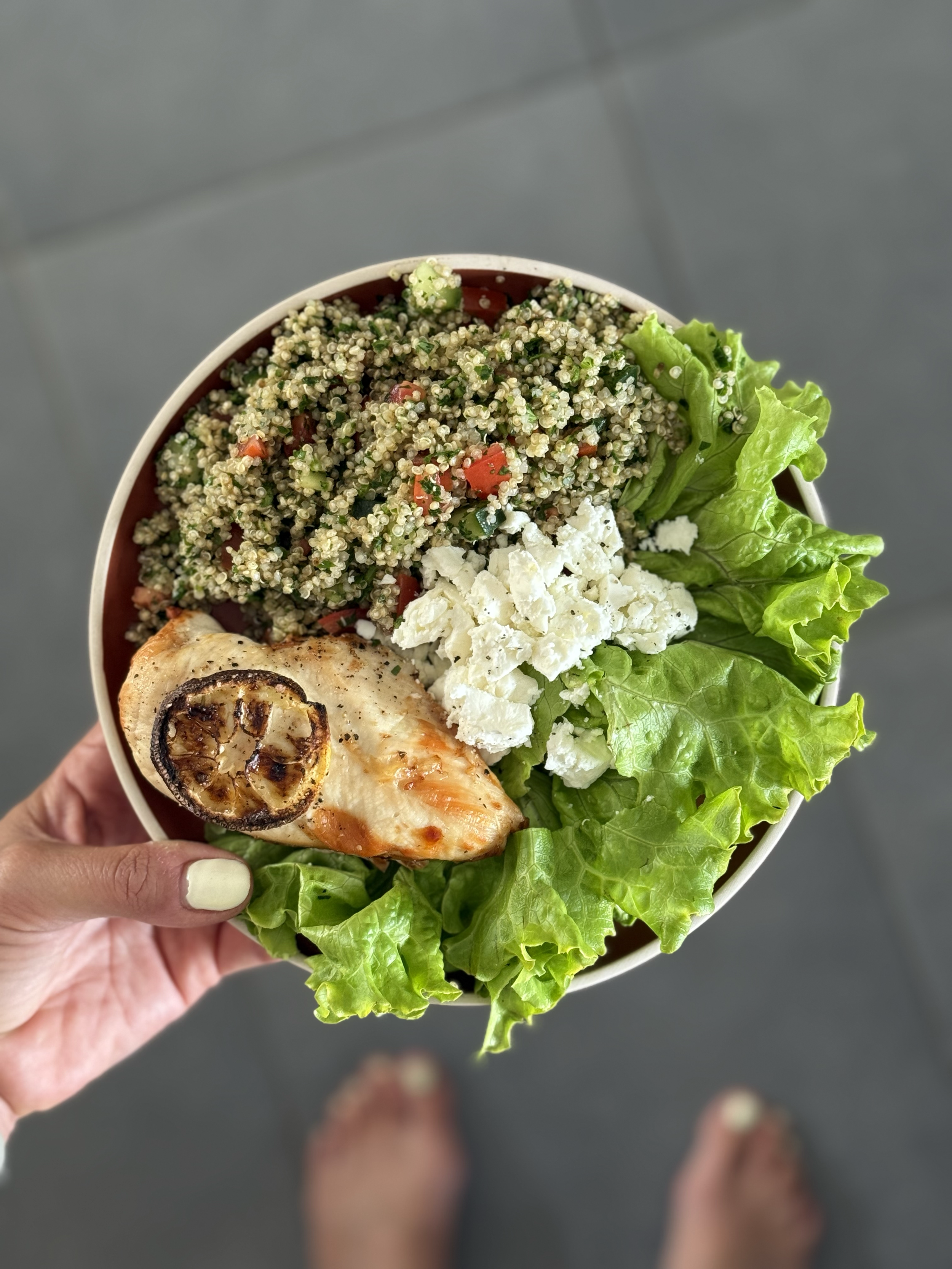 Recipe for diet without restriction. Personal nutrition coaching. Bowl of fresh healthy food including grilled chicken, lettuce, crumbled cheese, and quinoa salad with chopped vegetables, viewed from above.