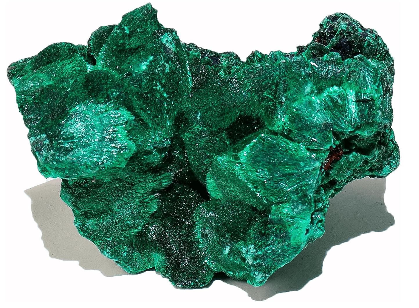 A large, irregularly shaped piece of vibrant green malachite mineral with a textured, banded surface, casting a shadow on a white background.