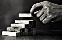 A hand stacking small blocks into a staircase