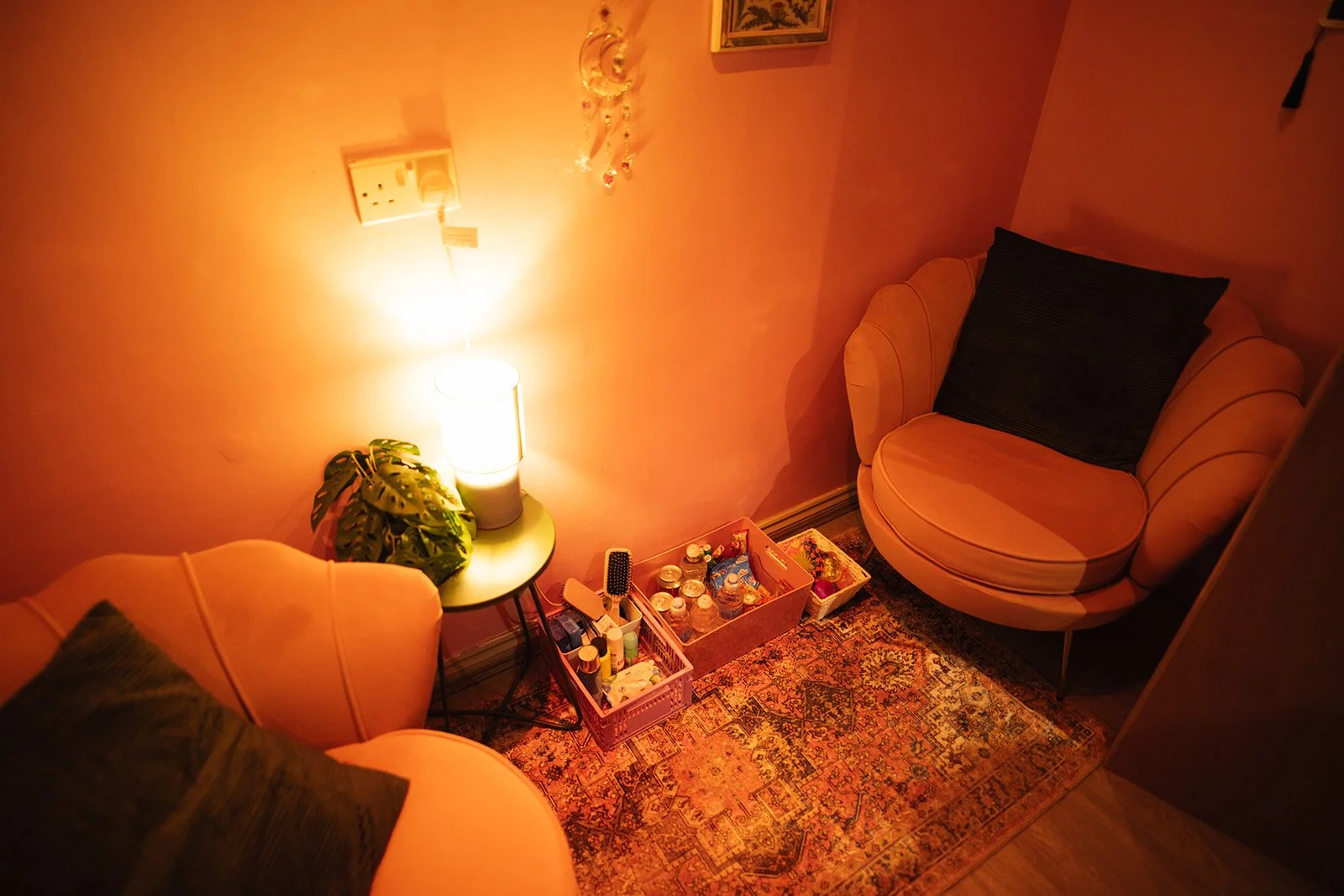 a pink room with two pink armchairs, and green side tables. The room is warmly lit.