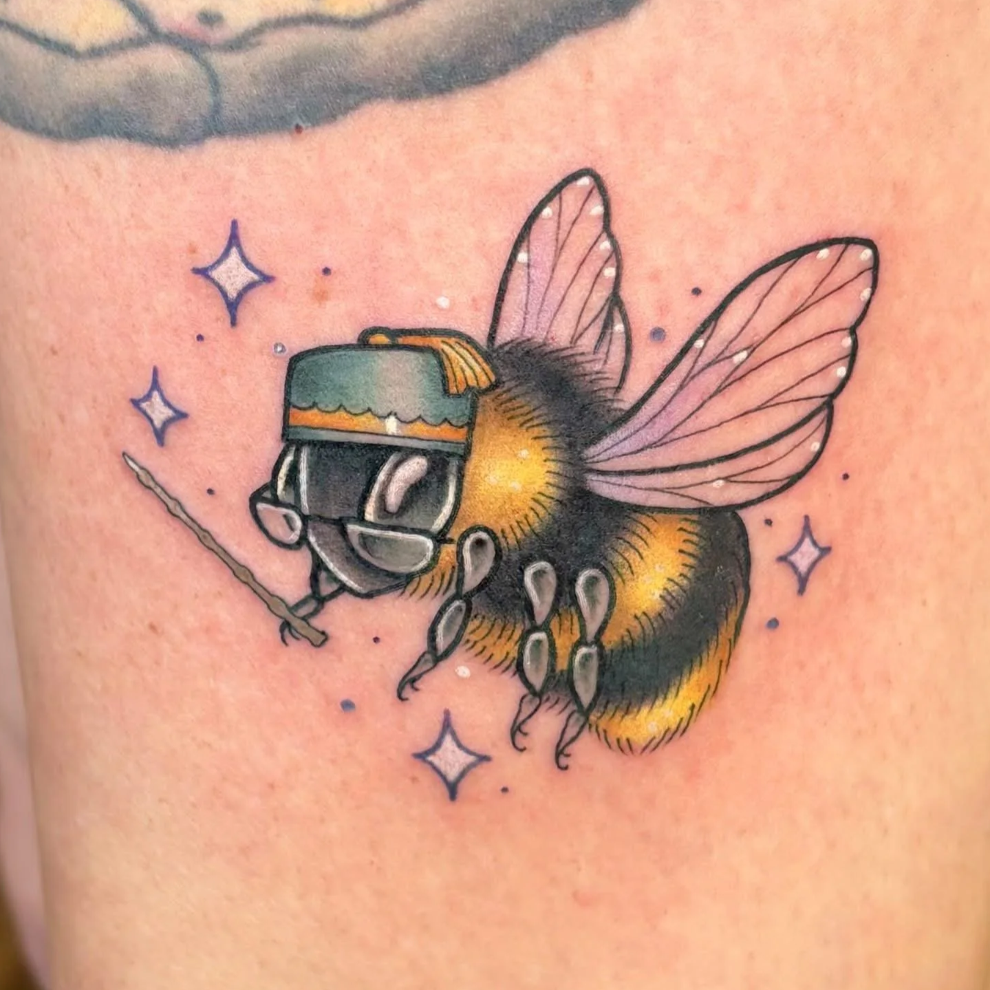 Whimsical bumblebee tattoo dressed as Albus Dumbledore, with tiny glasses, wizard hat in an illustrative neo-traditional style